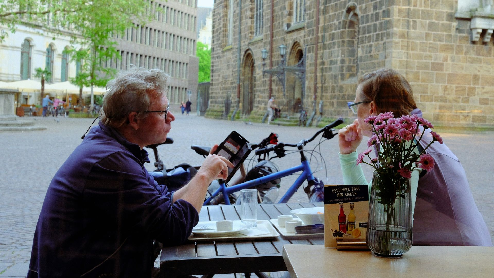 Two people sitting at an outdoor cafe table.