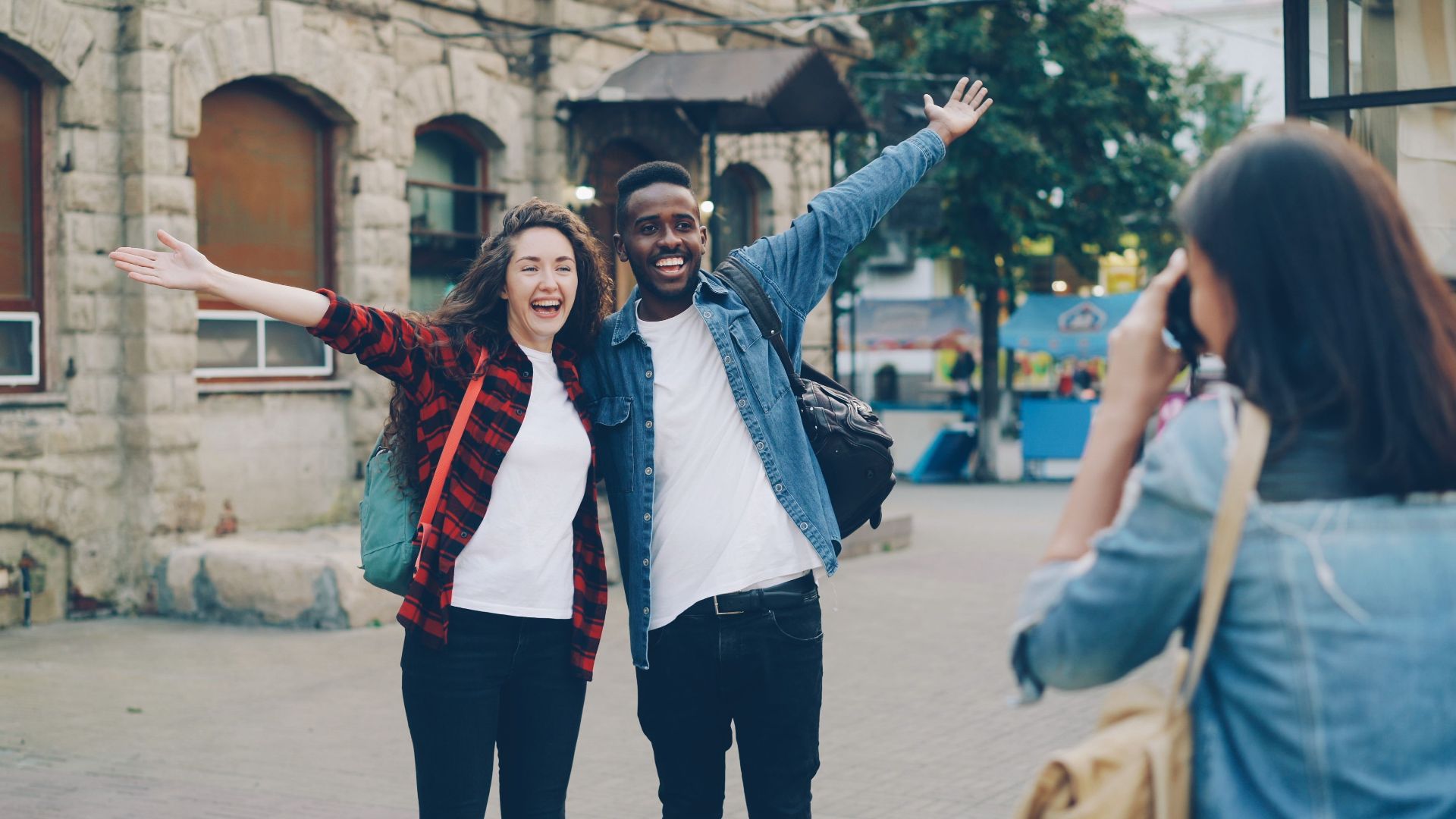 Two cheerful travelers posing for a photo in a city street, capturing joyful memories.