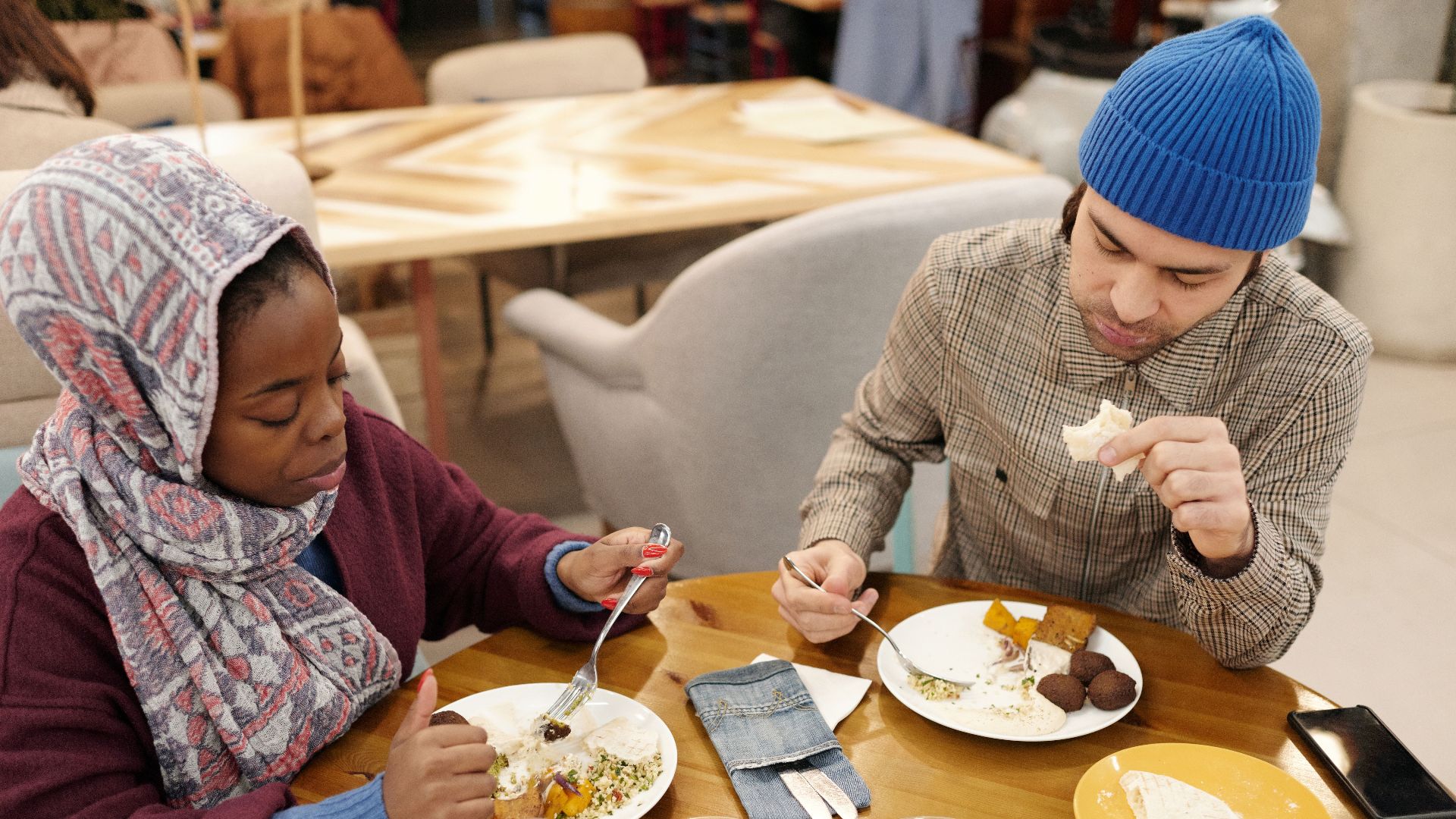 A multiethnic couple dining indoors, enjoying a Middle Eastern meal.