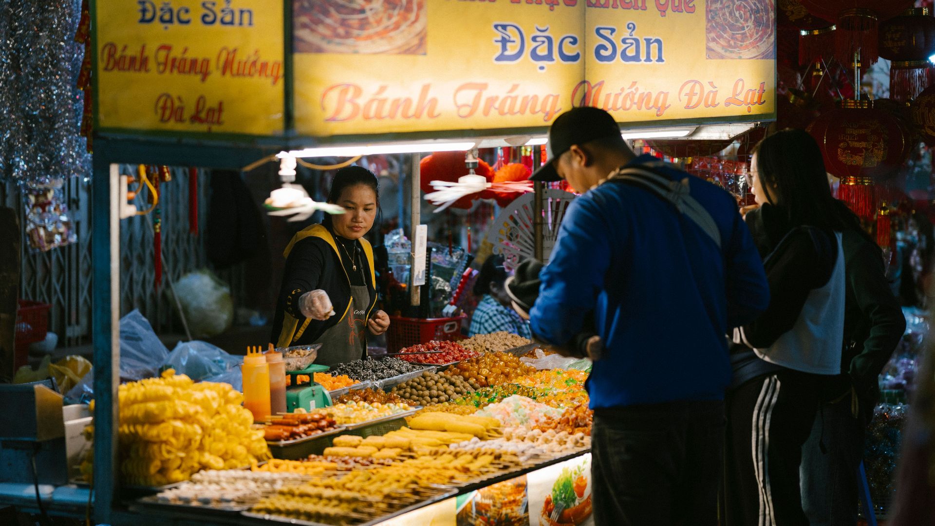 Vibrant night market scene with a Vietnamese food stall offering diverse local snacks and delicacies.