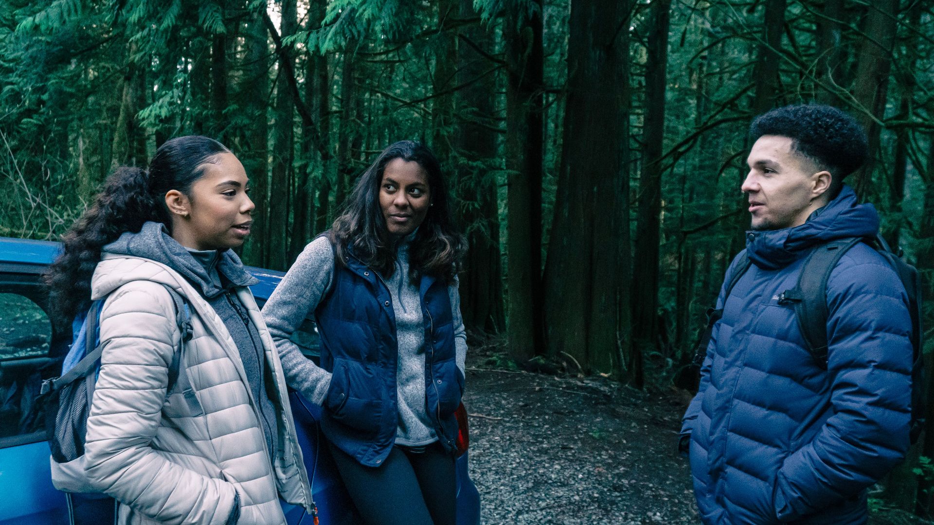 A diverse group of friends in jackets enjoying a conversation in the forest.