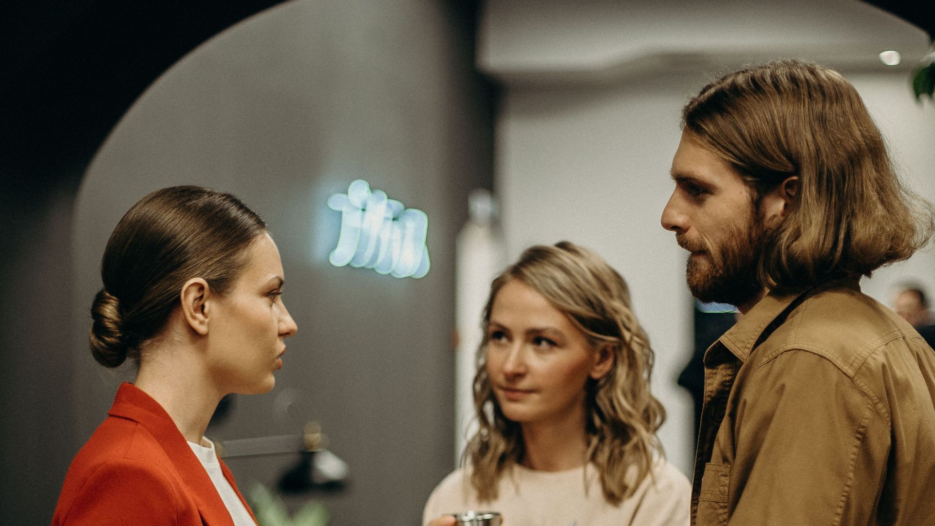 Three colleagues having a discussion in a modern office setting.