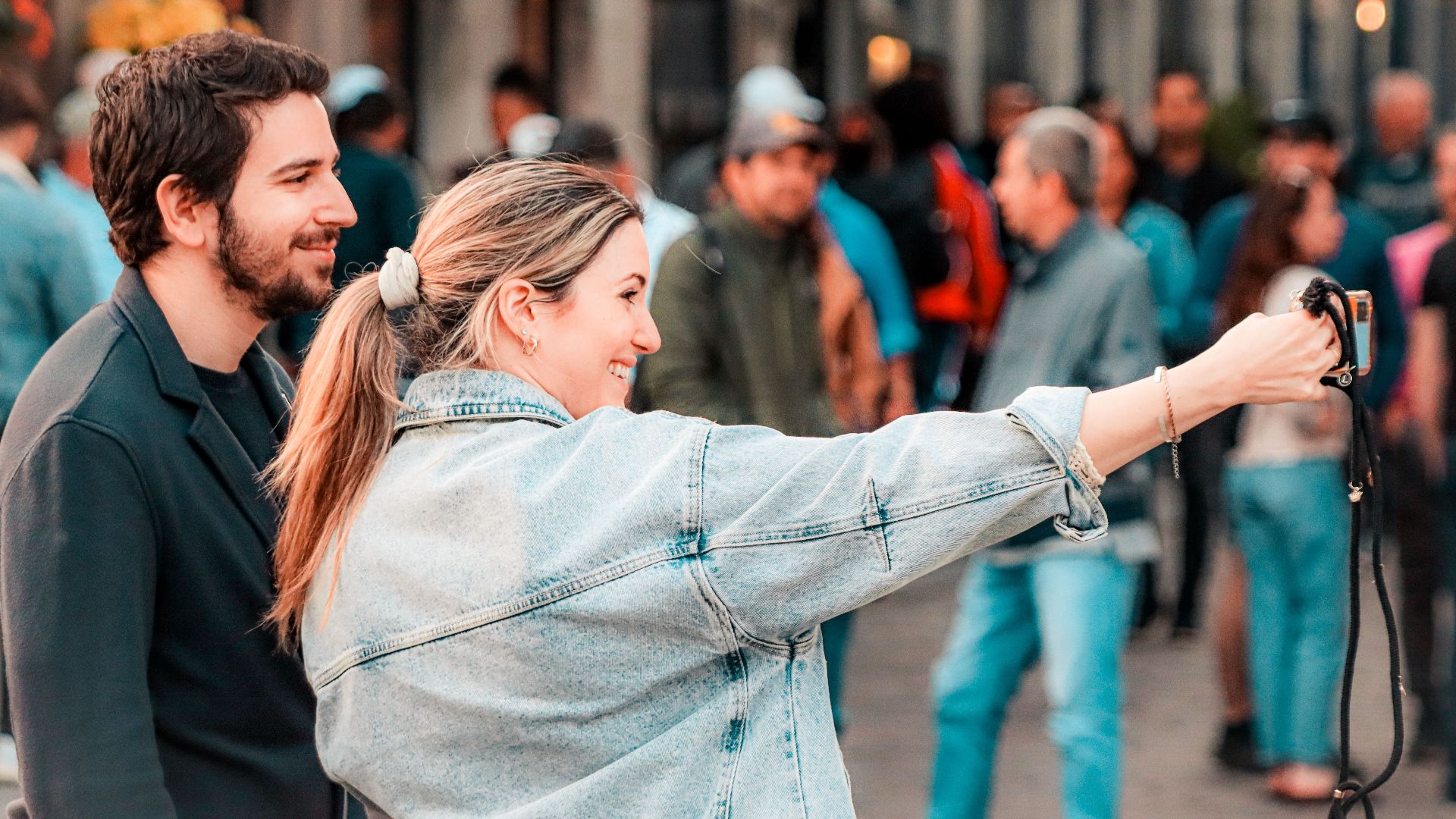 Young couple taking a selfie in a bustling street of Montréal, capturing the lively atmosphere.
