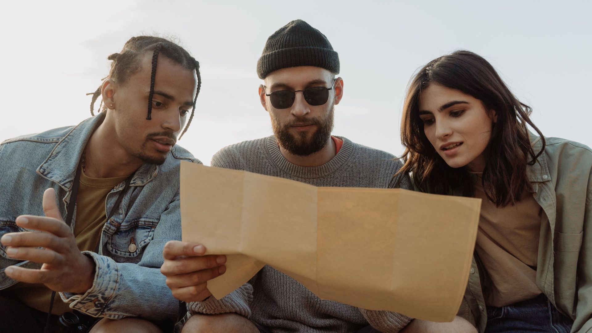 Group of diverse friends reading a map outdoors, exploring and planning their adventure.