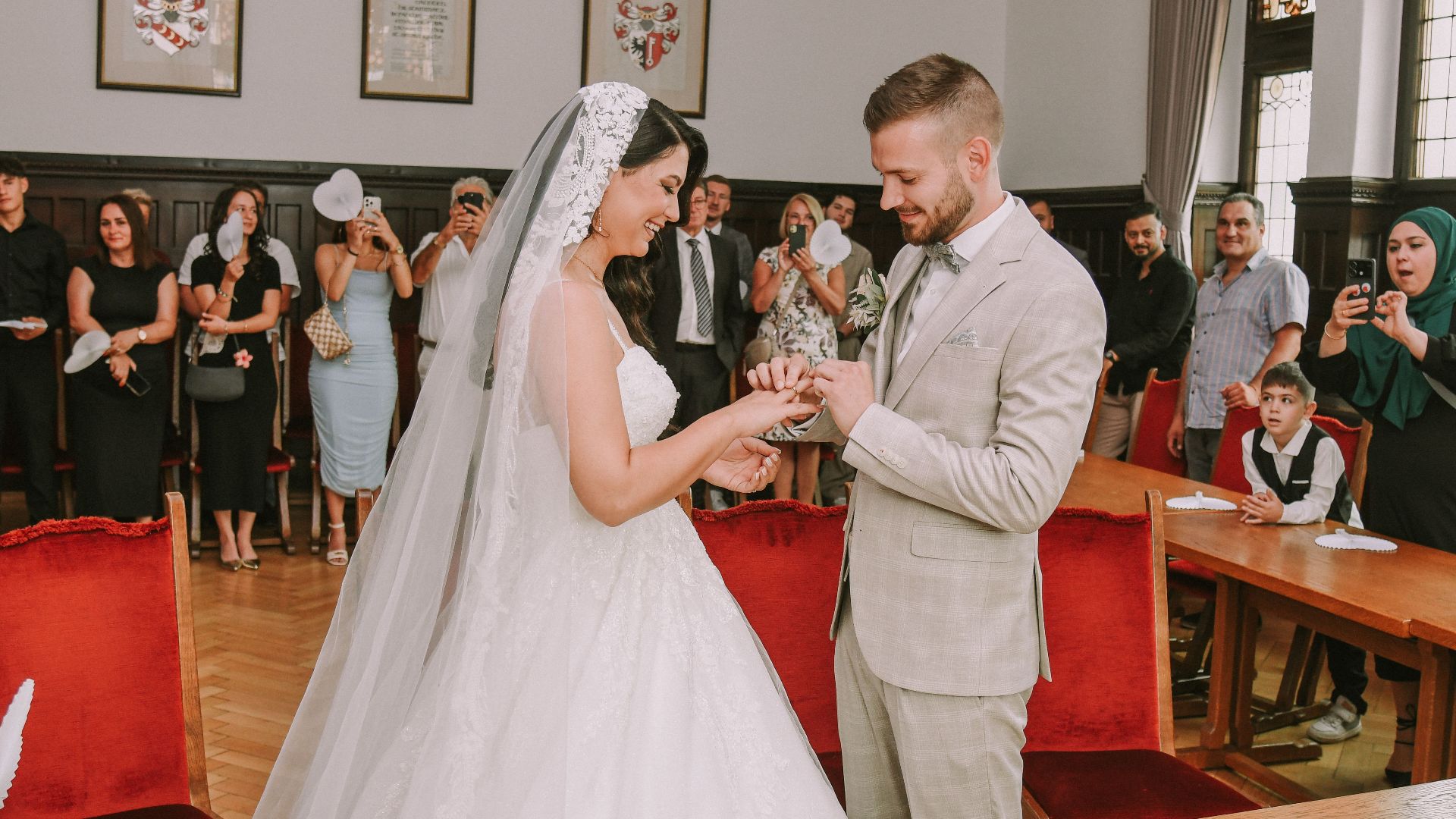 Bride and groom exchanging rings in a beautiful wedding ceremony indoors with guests.