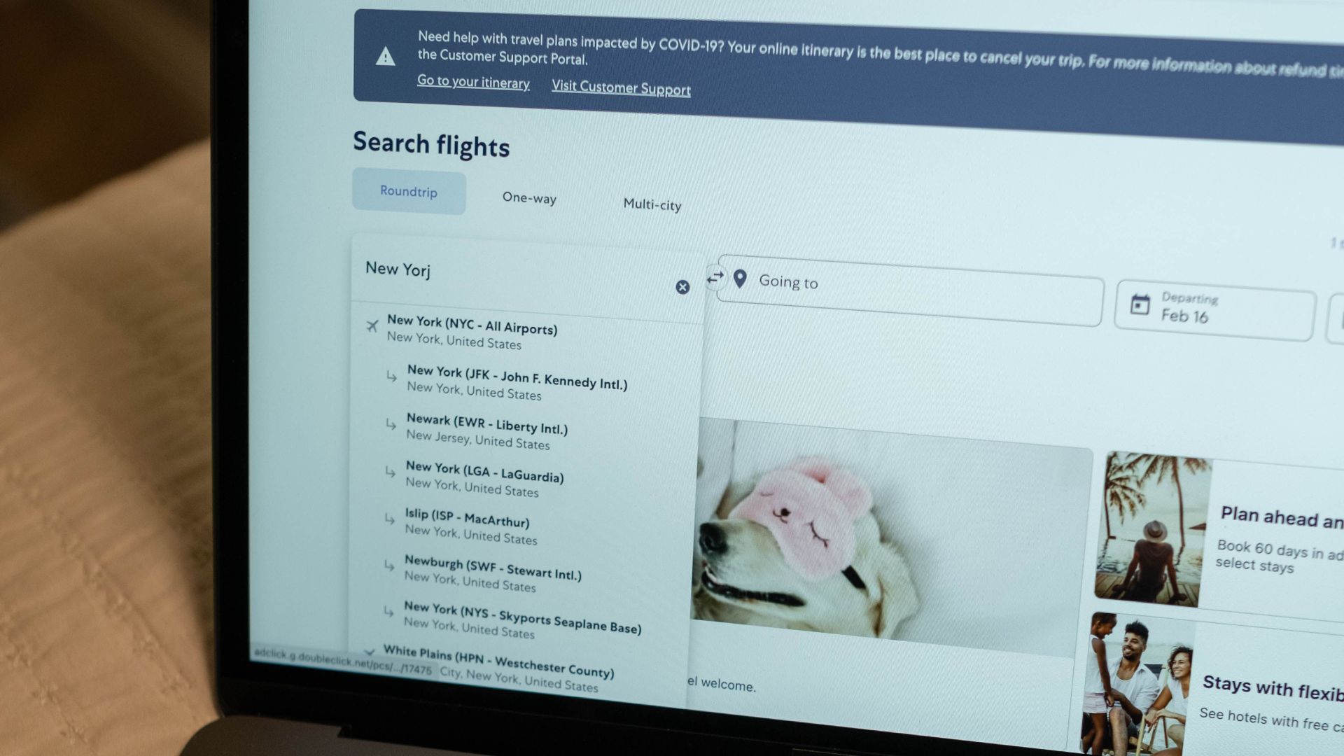 Person typing on laptop, searching flight details indoors, focusing on travel planning and booking.