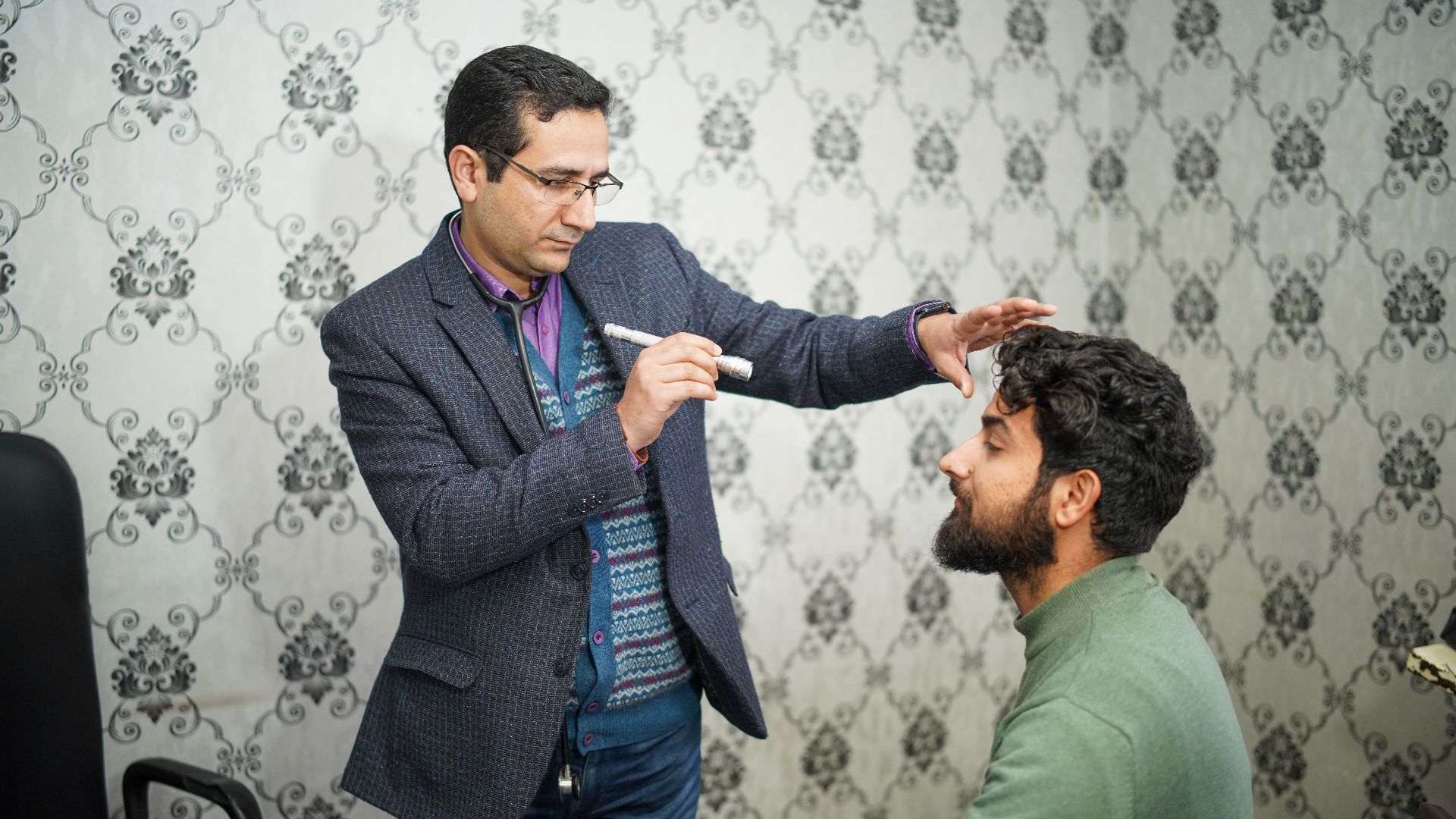 A doctor performs an eye examination on a patient in a clinical setting.