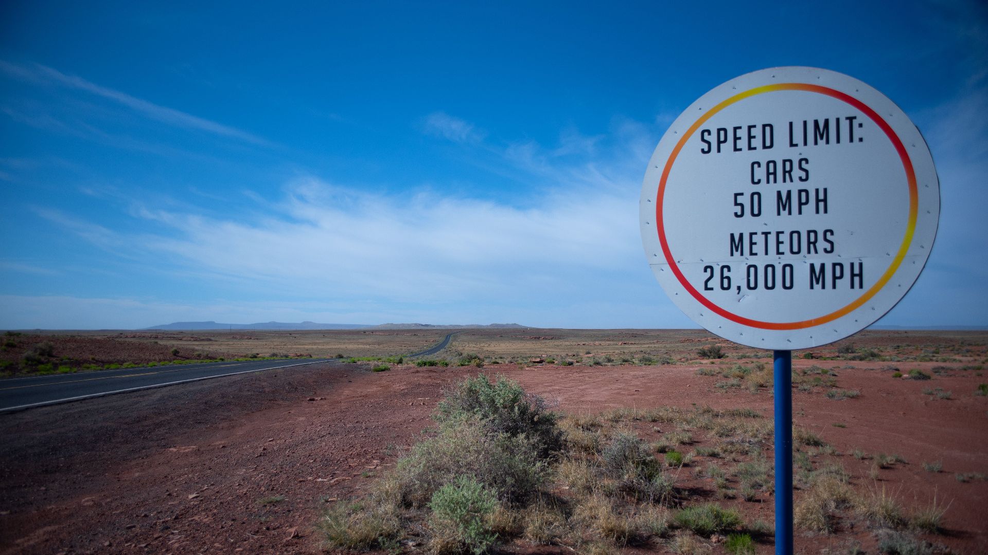 Funny speed limit sign in the Arizona desert, highlighting cars and meteor speeds.