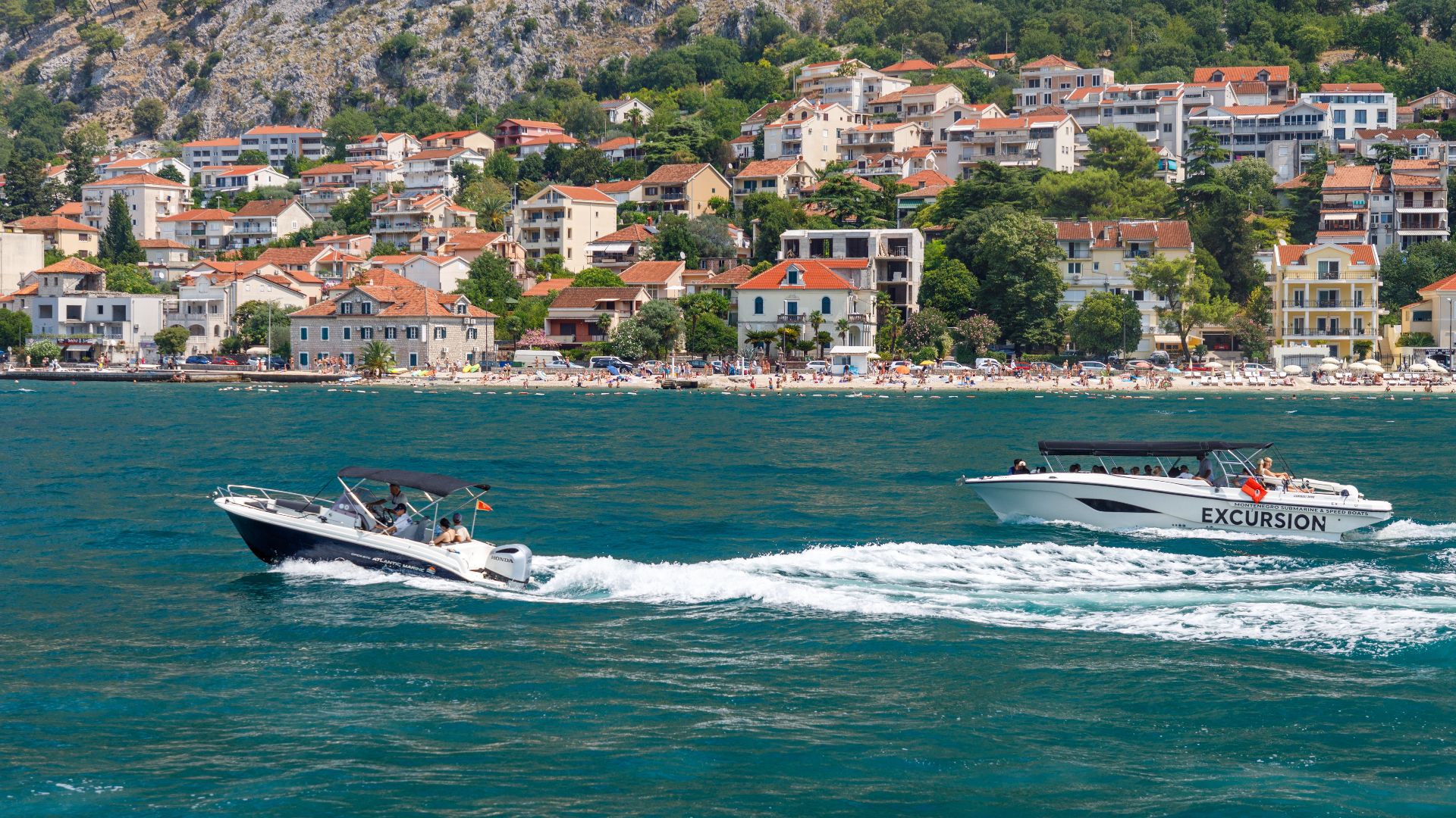 Two boats cruising along the Adriatic coast with a scenic coastal town backdrop.
