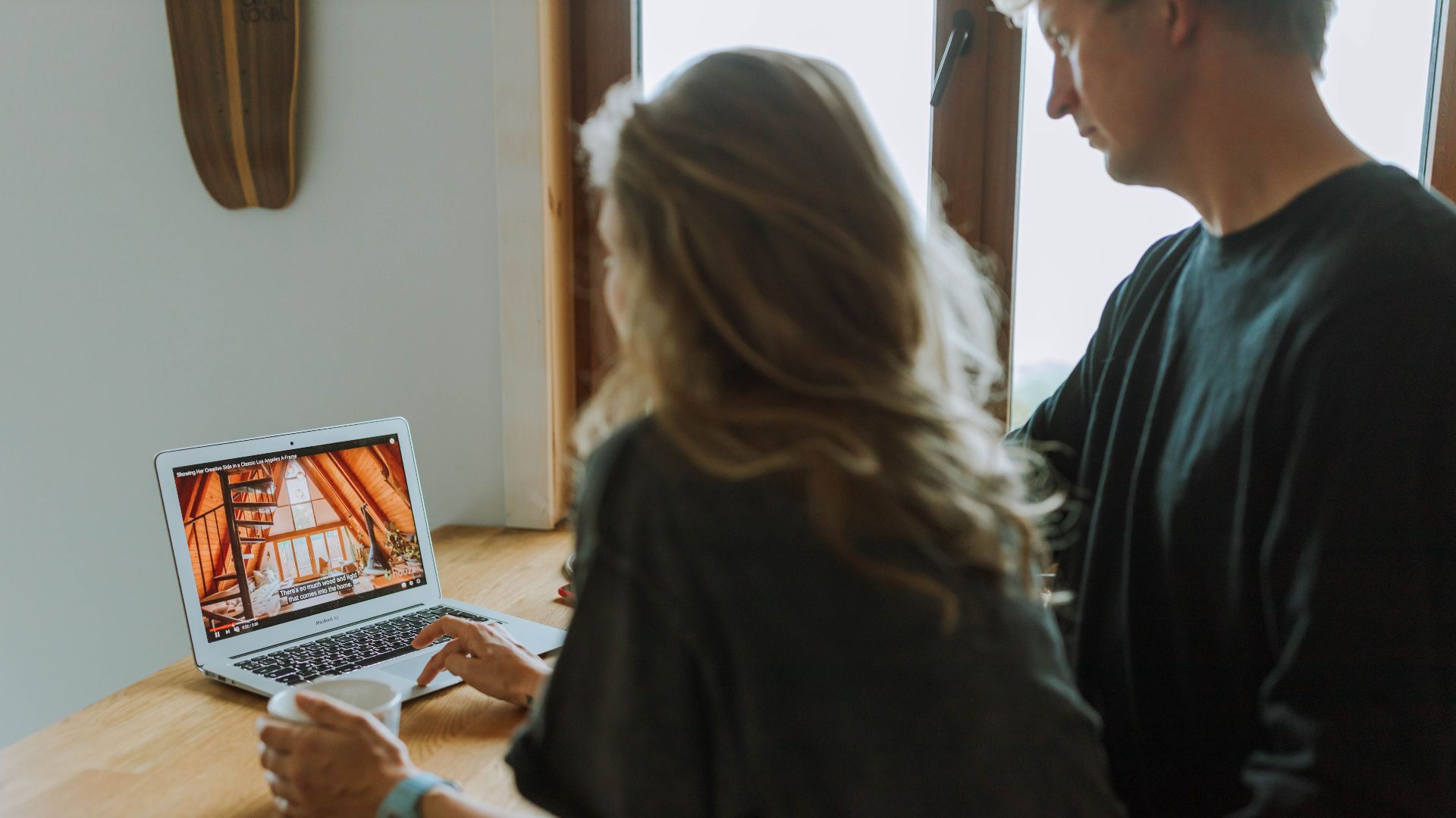 A couple viewing home interior design on a laptop while enjoying coffee together indoors.