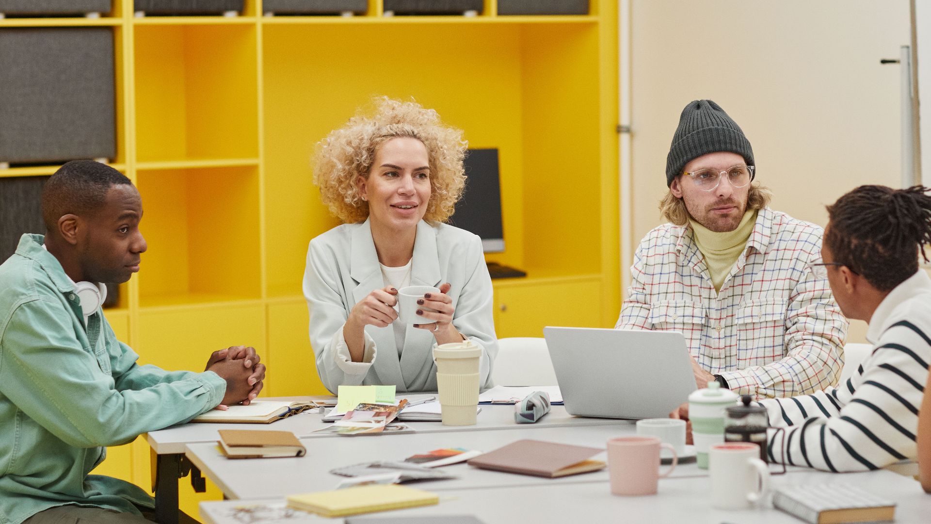 A diverse group of coworkers engaging in a meeting around a table in a modern office setting.