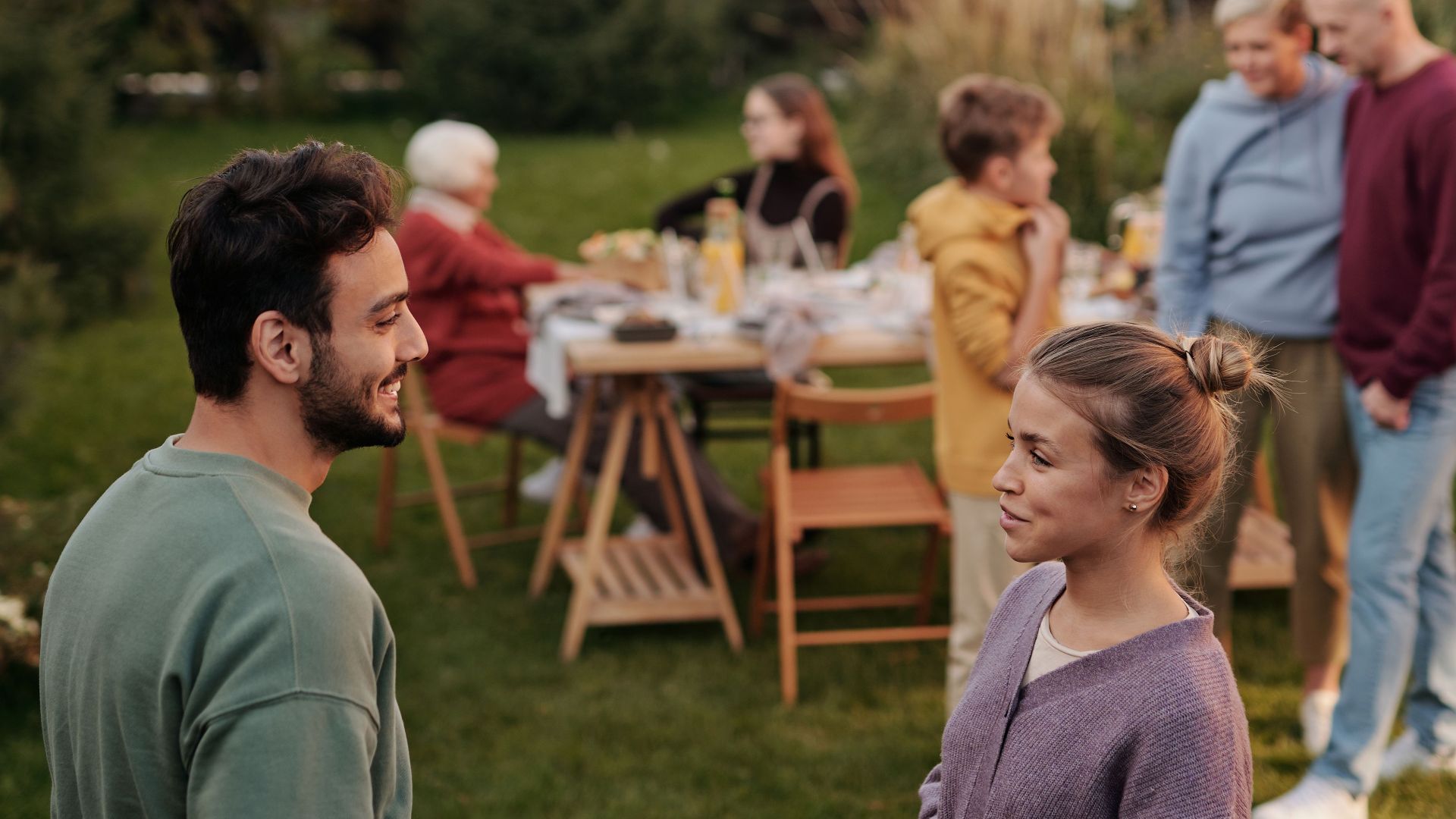 A warm family gathering outdoors with people chatting and enjoying the day.