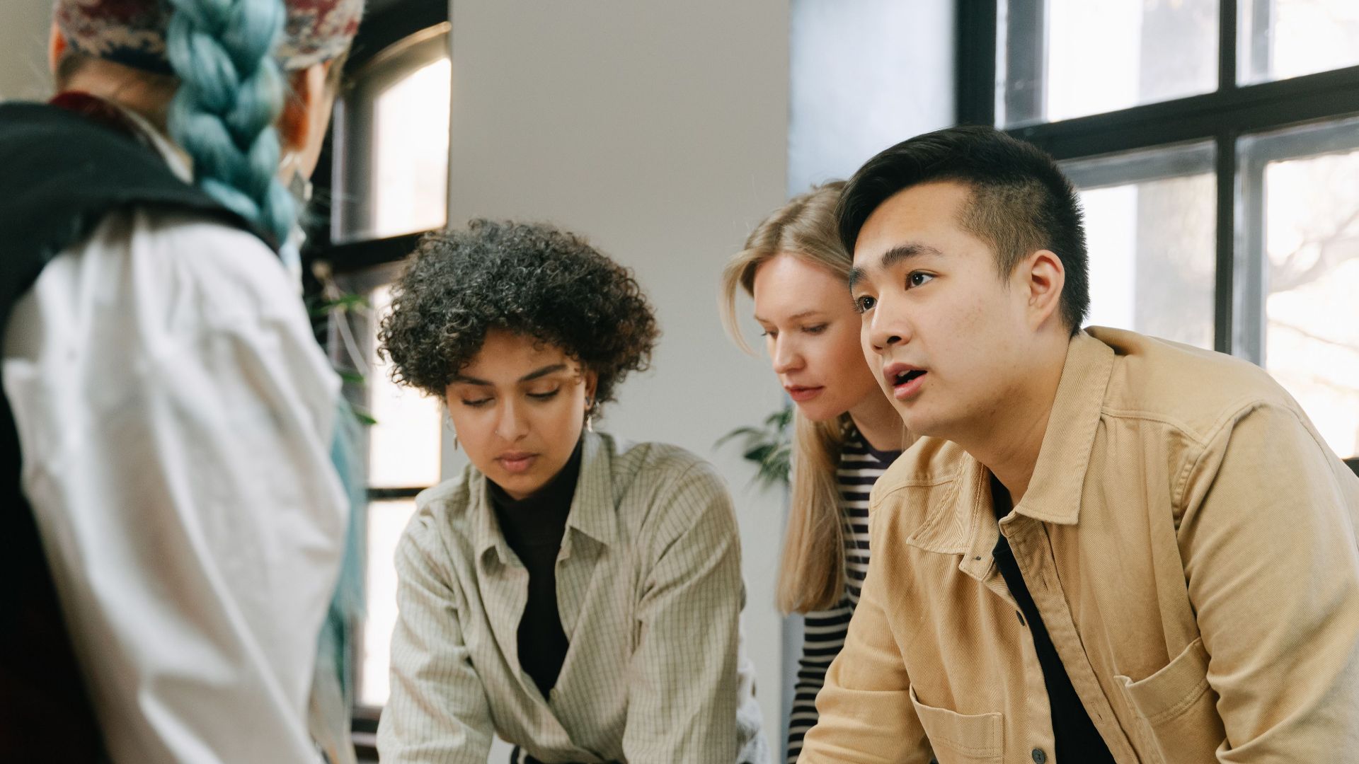 A diverse group of coworkers engaged in a collaborative meeting in a modern office setting.