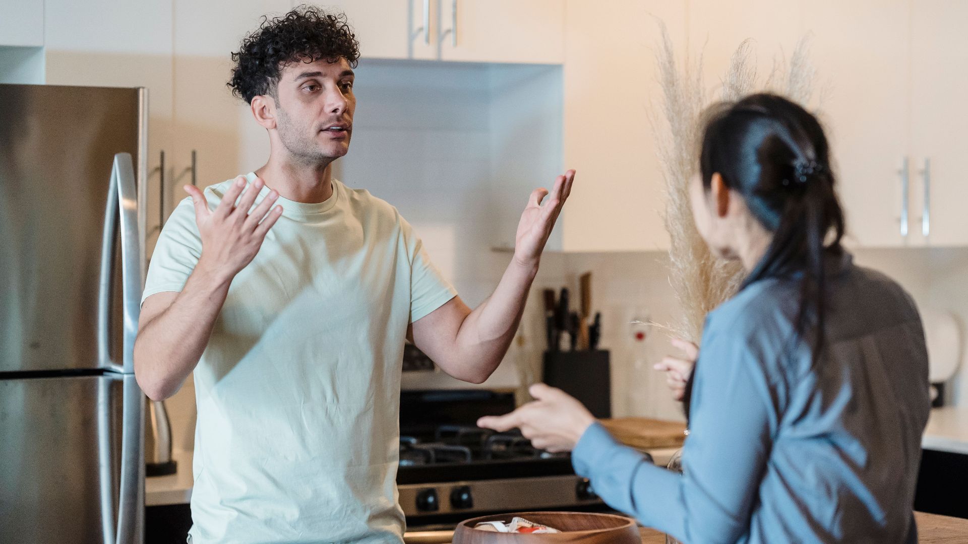 A couple in a tense conversation in a modern kitchen, expressing emotions.
