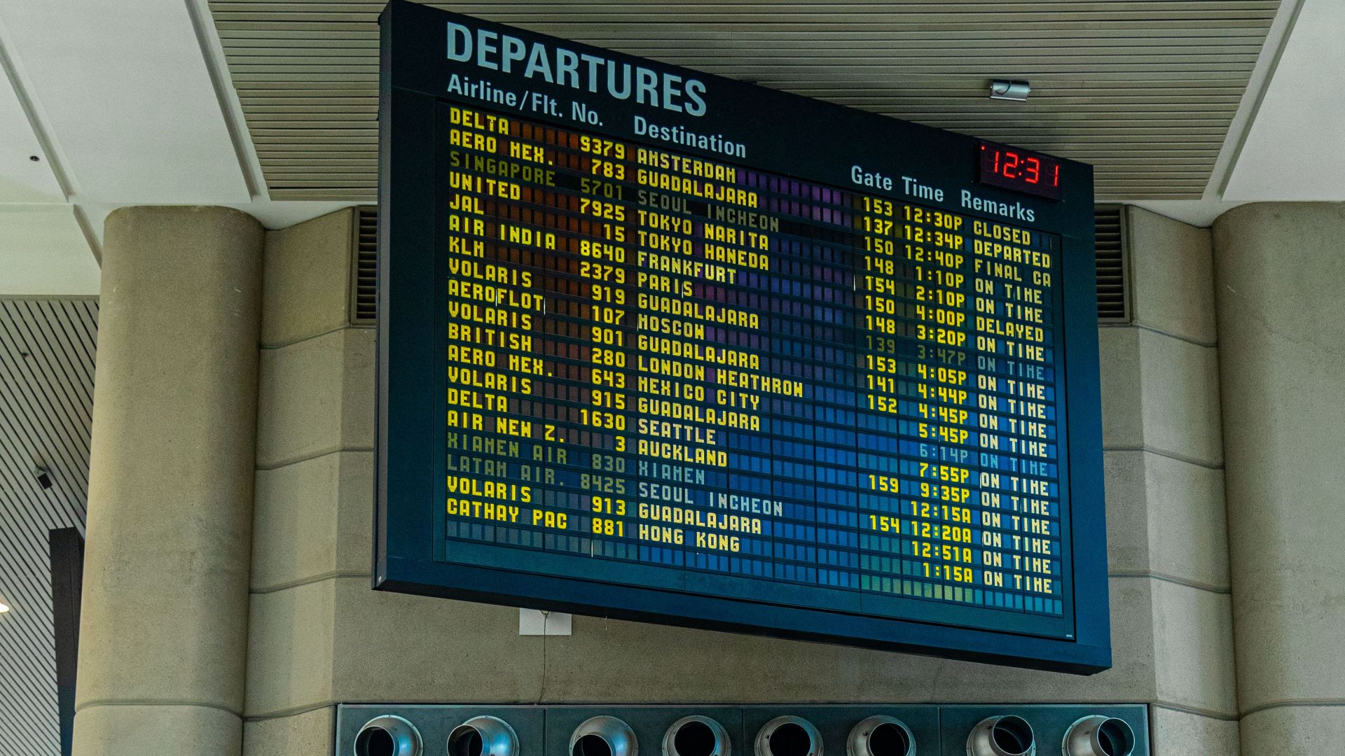 Digital departure board and airline check-in counters inside a modern airport terminal.