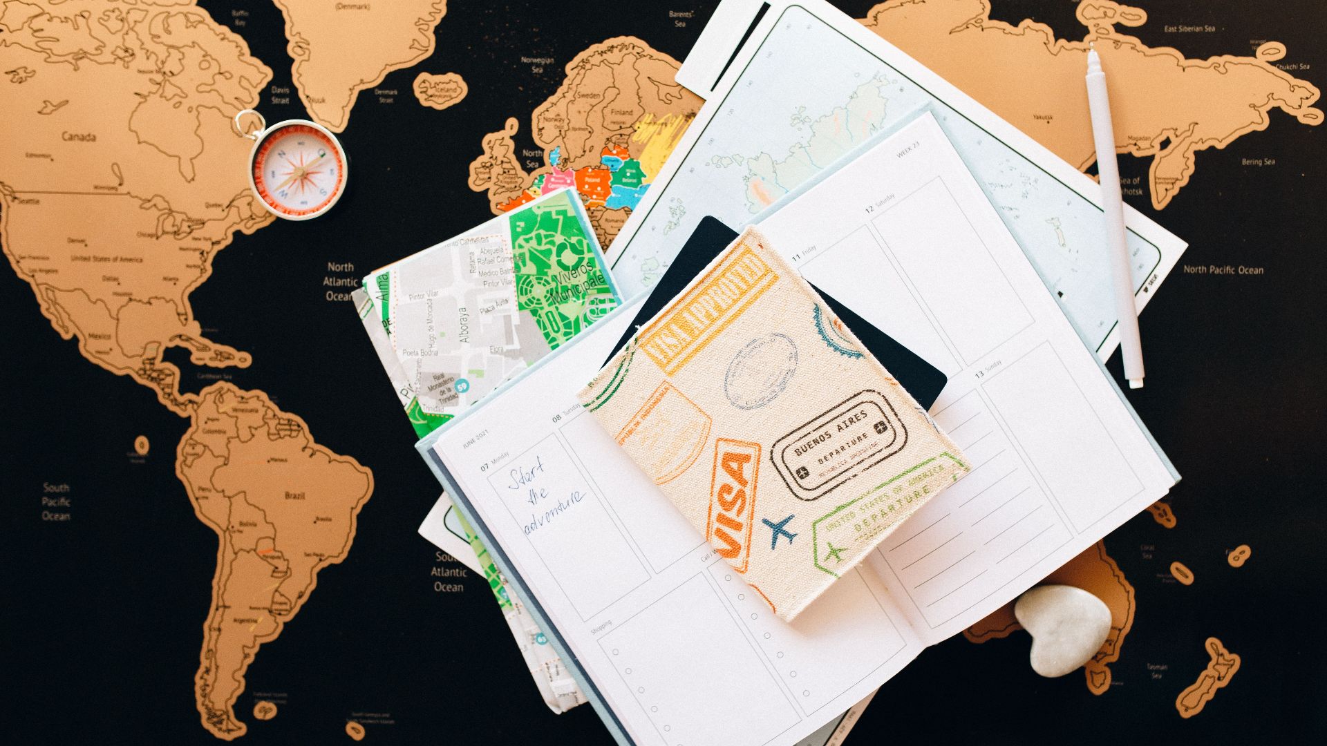 A flat lay of travel planning items on a map, featuring a compass, notebook, and guide for wanderlust enthusiasts.