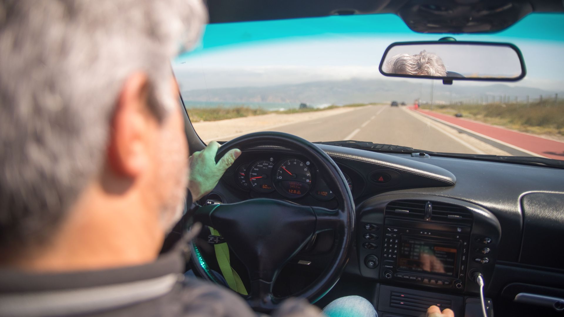 A person driving a car on a scenic highway in Portugal on a sunny day.
