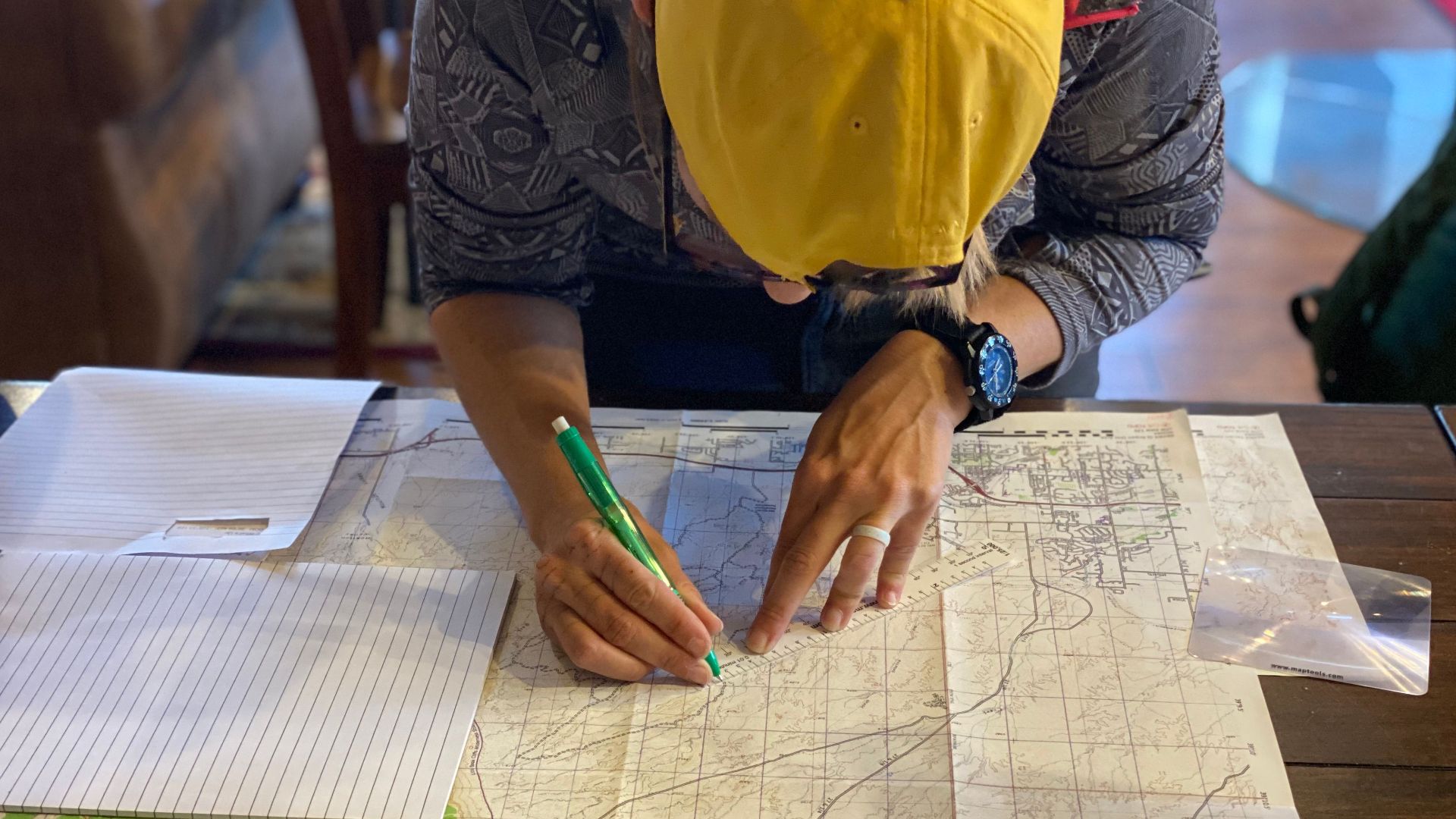 Individual mapping out a route indoors using a map and pen, possibly planning a journey.