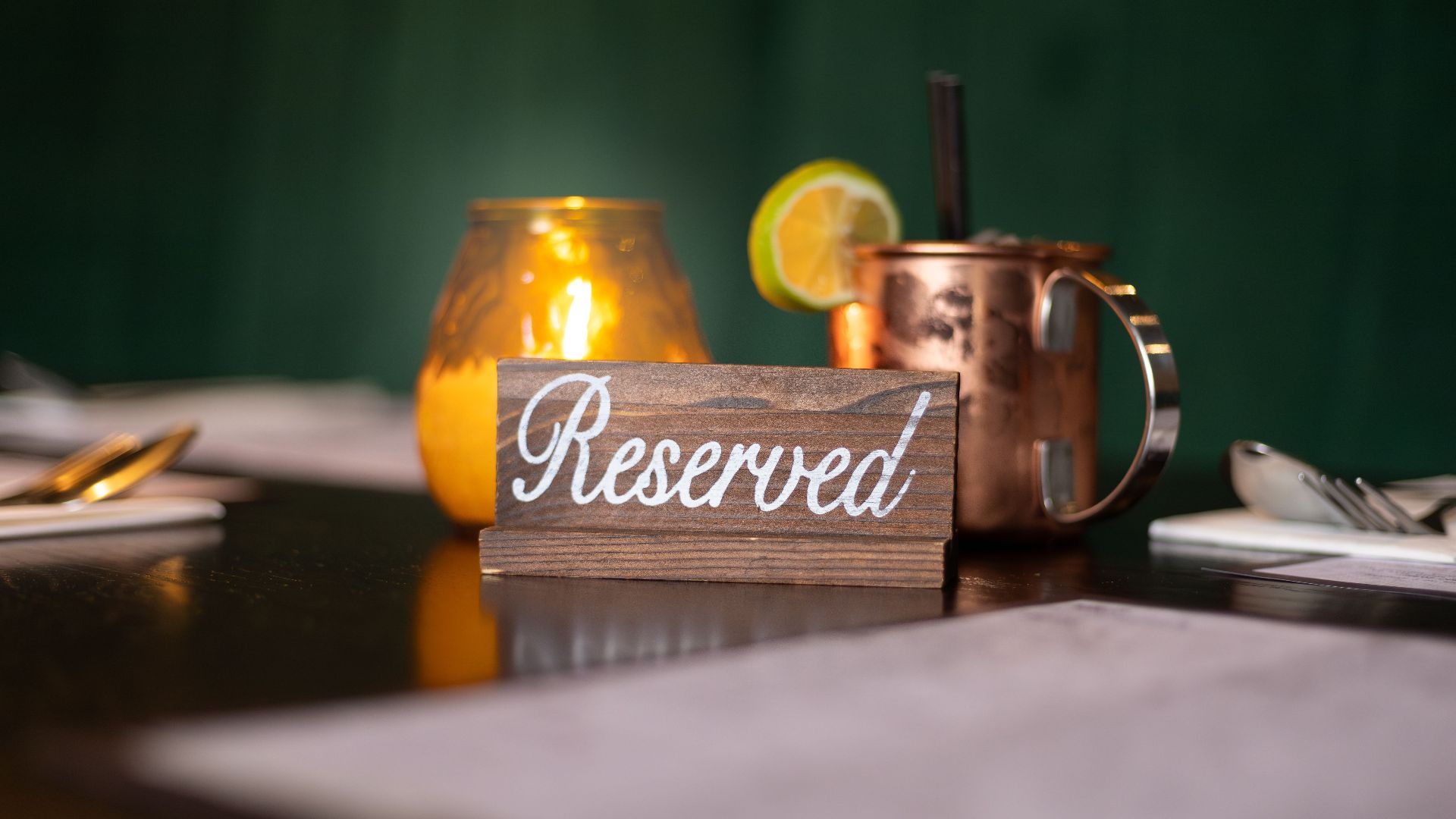 A warmly lit table featuring a reserved sign and a glowing candle, perfect for dining experiences.