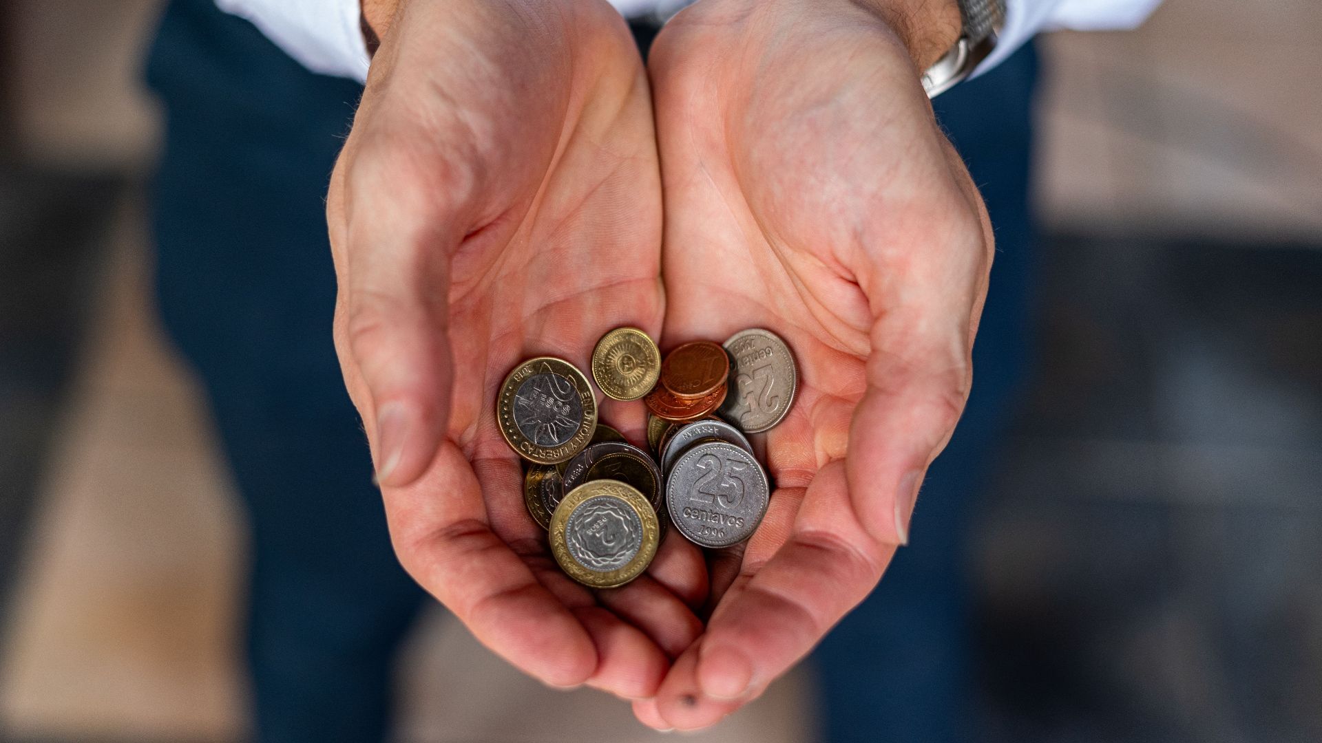 Close-up of hands holding Argentine coins, showcasing currency detail in Buenos Aires.