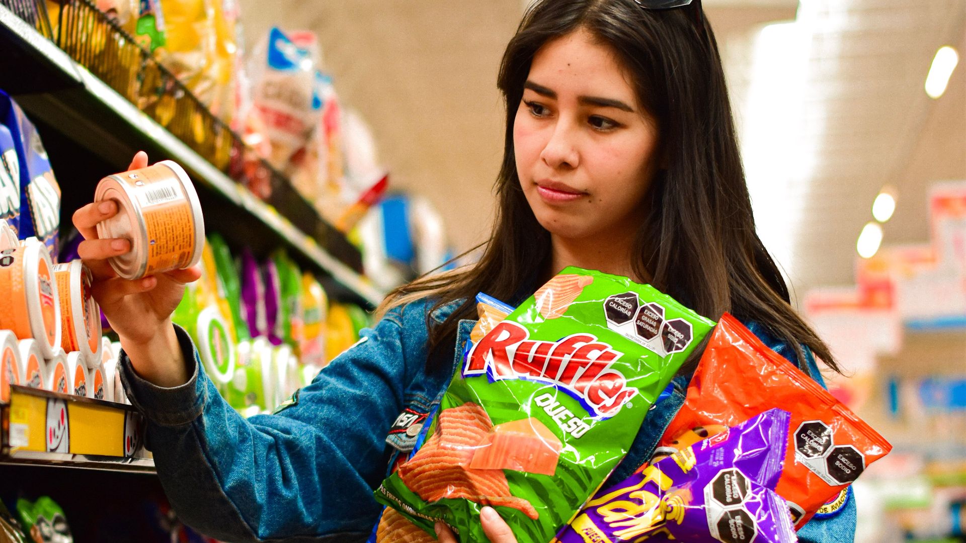 Woman selecting crisps in Texcoco, Mexico supermarket aisle.