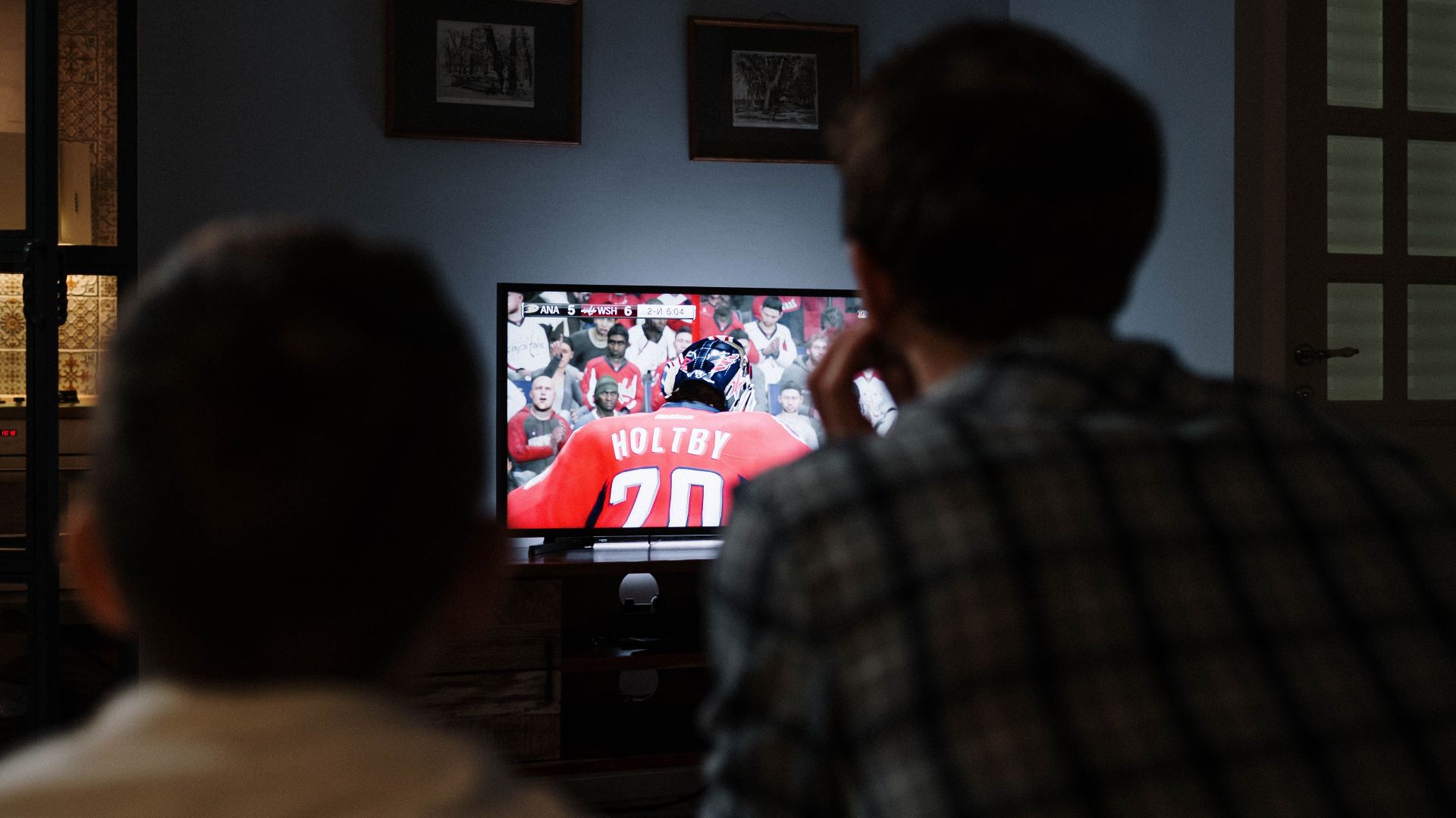 Father and son enjoying a hockey game together on TV from their living room.