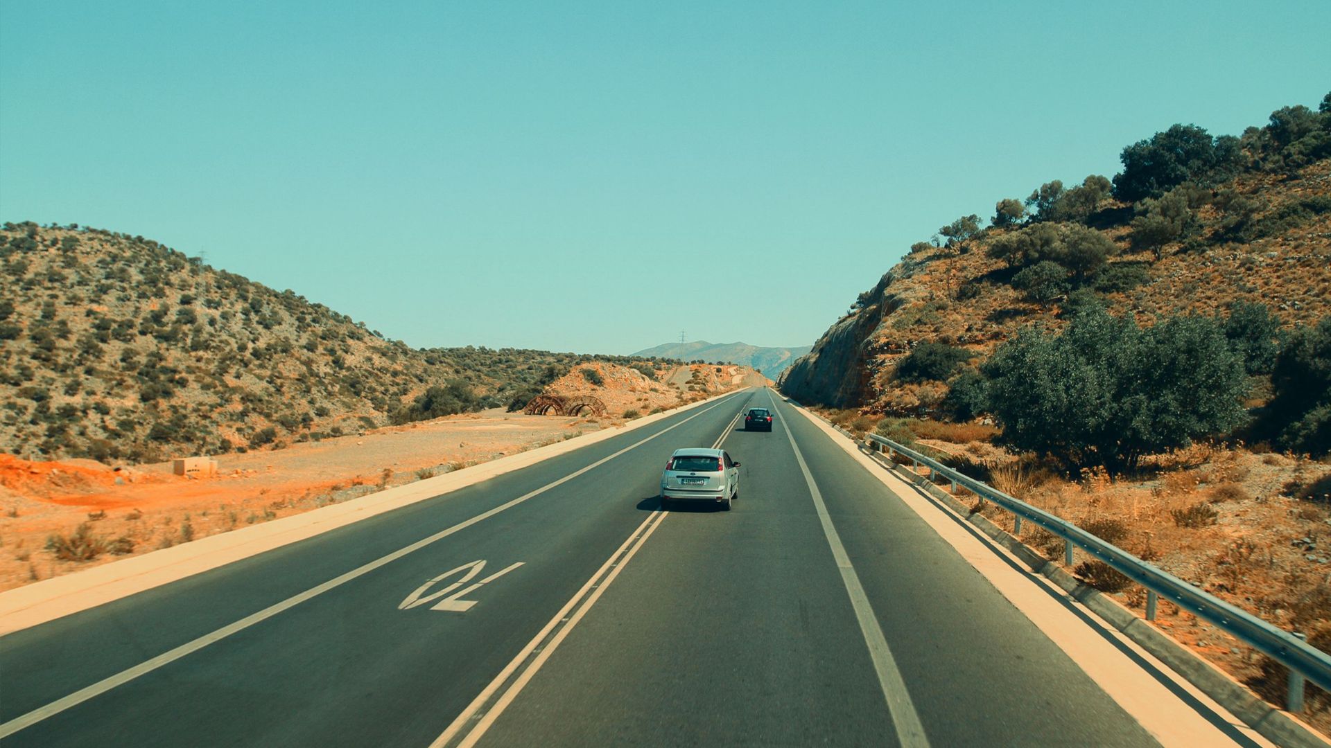 A view of a highway through a desert landscape with cars and clear skies.