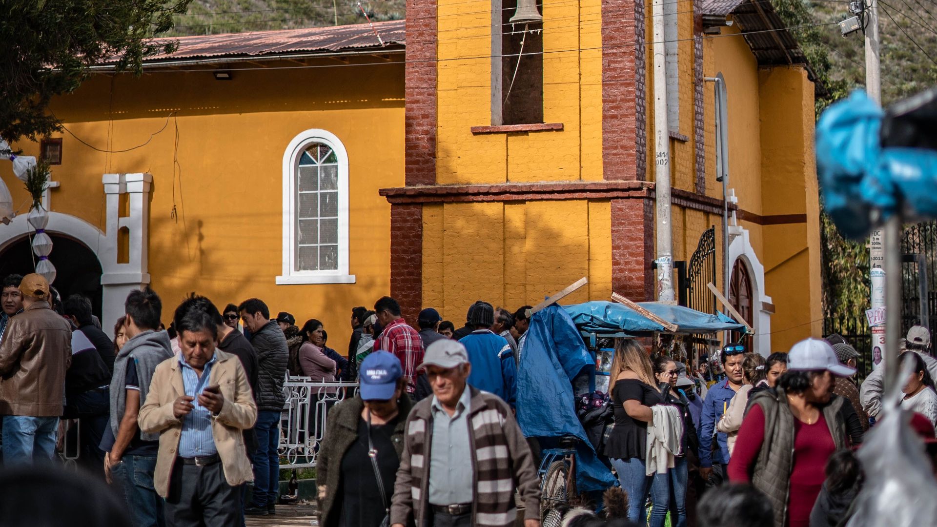 Colorful church gathering in rural Peru with mountains in the background.