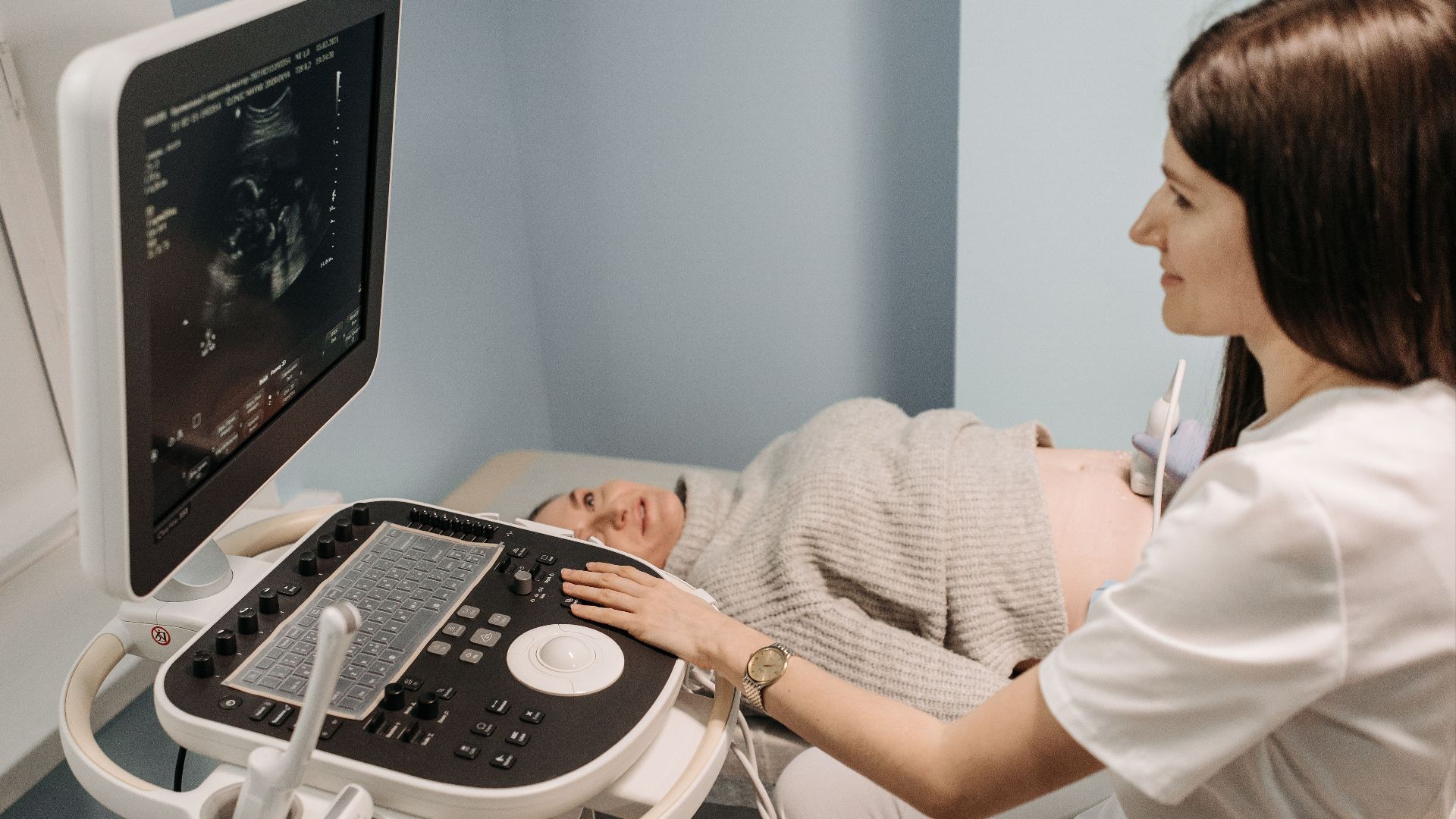 A healthcare professional performing an ultrasound on a pregnant woman in a clinic setting.