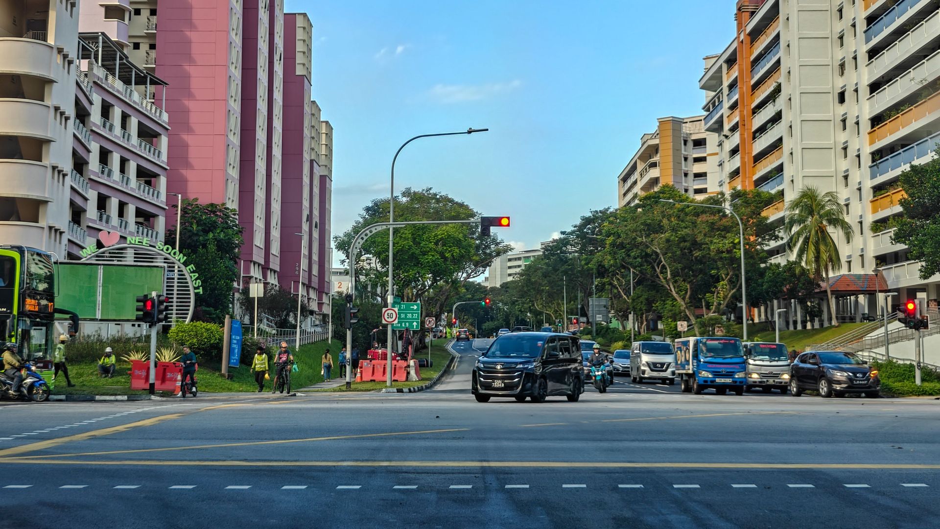 Busy urban street with colorful buildings and vehicles under a clear blue sky.