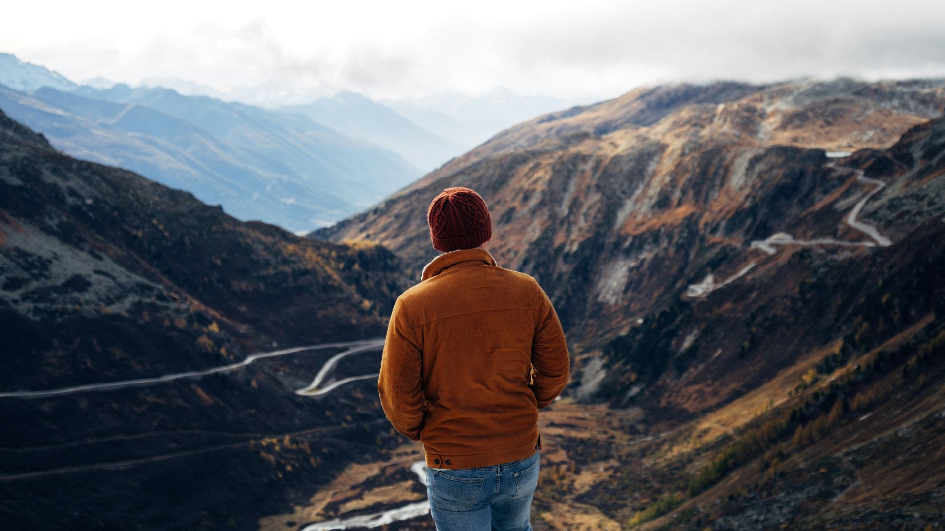 person wearing brown knit cap standing on brown mountain