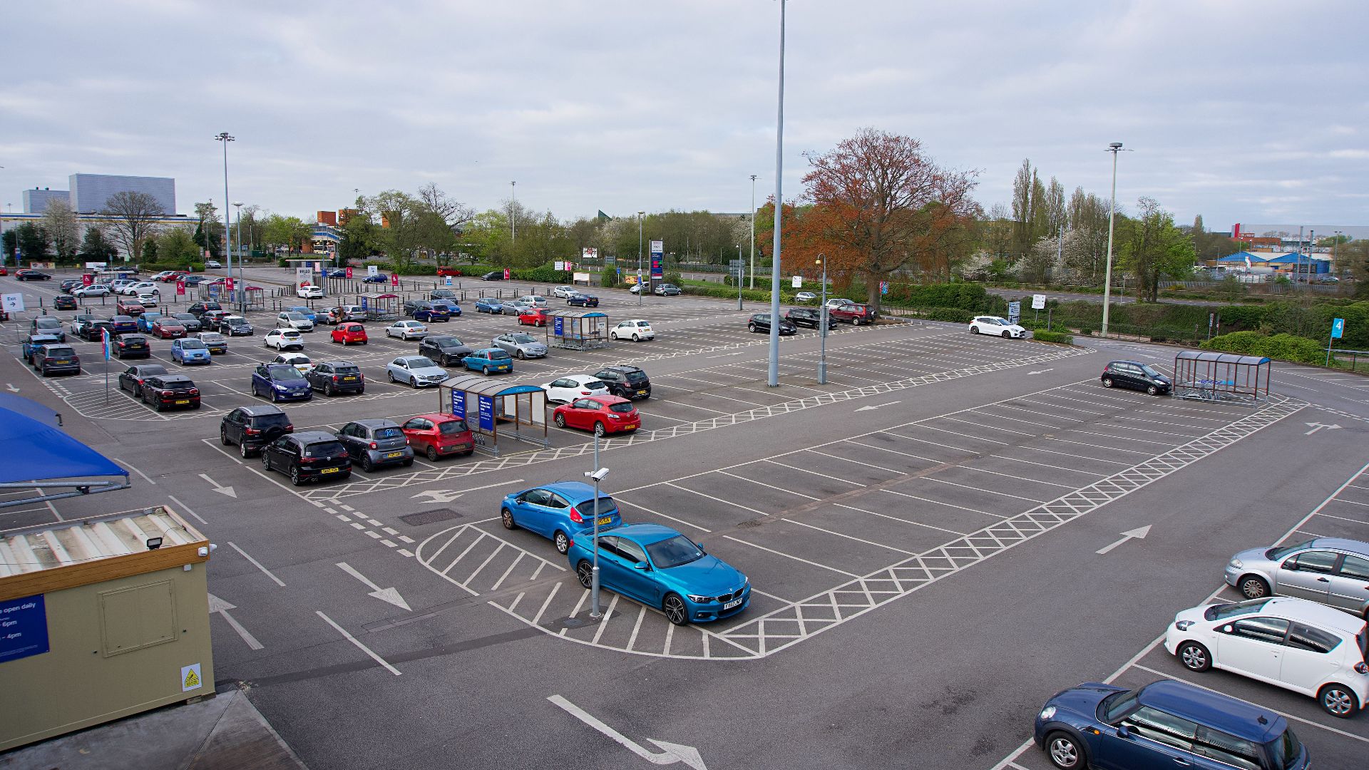 High-angle view of an expansive parking lot with scattered vehicles in England, showcasing urban infrastructure.