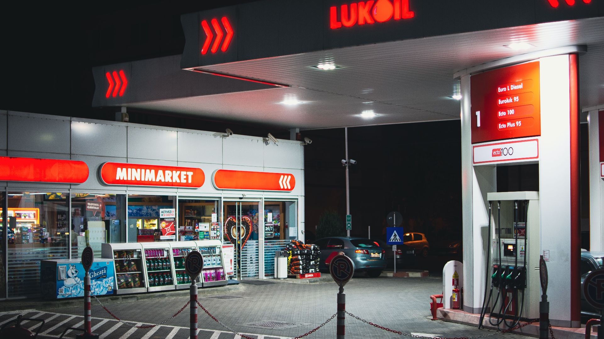 A brightly lit gas station with a minimarket in Bucharest during nighttime.