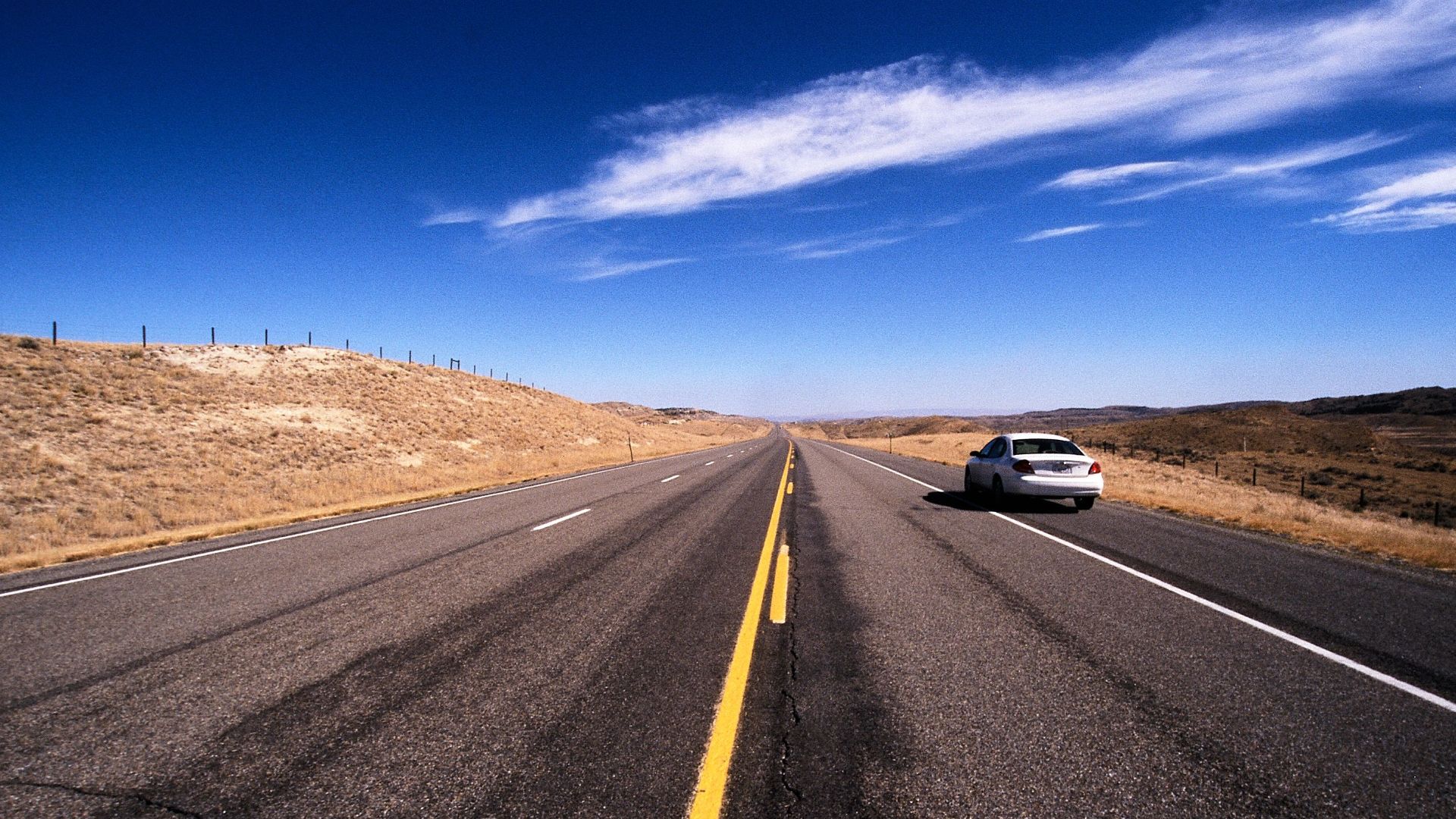Explore the vast open road in Wyoming under a clear blue sky.