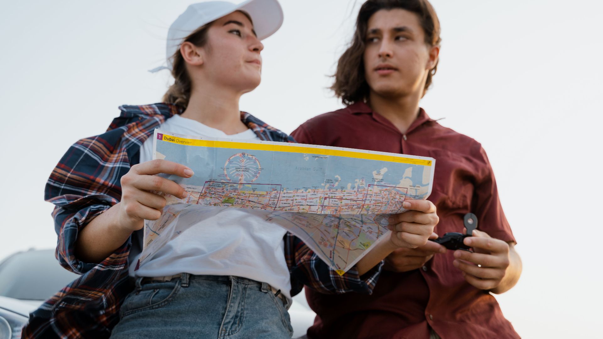 A young couple examining a map outdoors, planning their travel journey together.