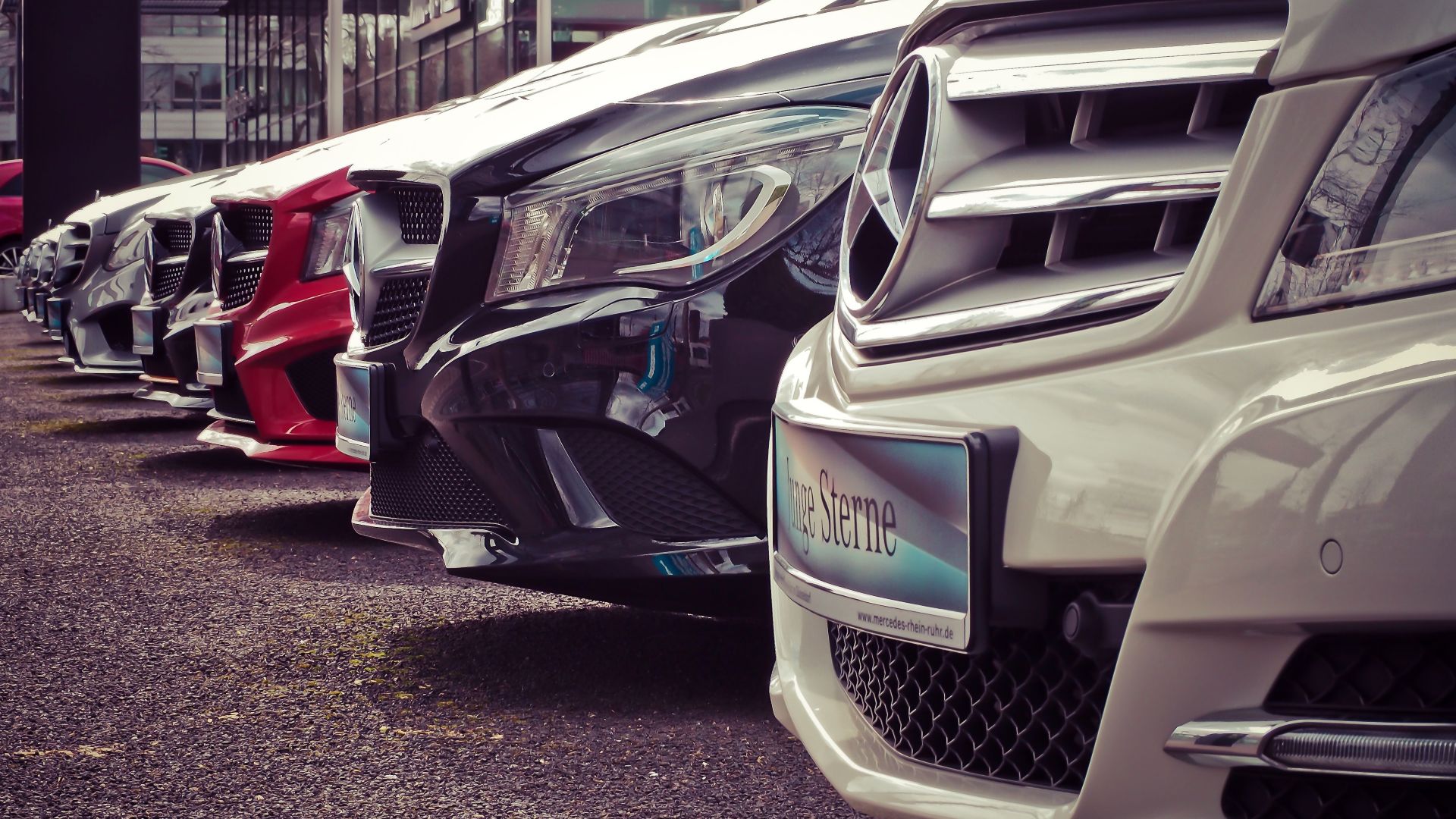 Luxury cars lined up at an outdoor dealership, showcasing sleek designs.