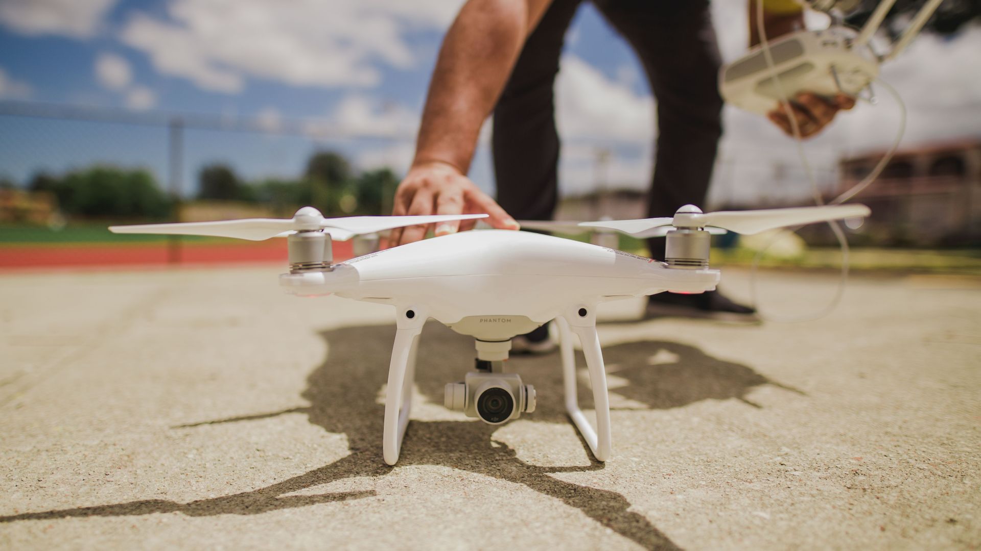 A white drone is prepared for flight on a sunny day with blue skies.