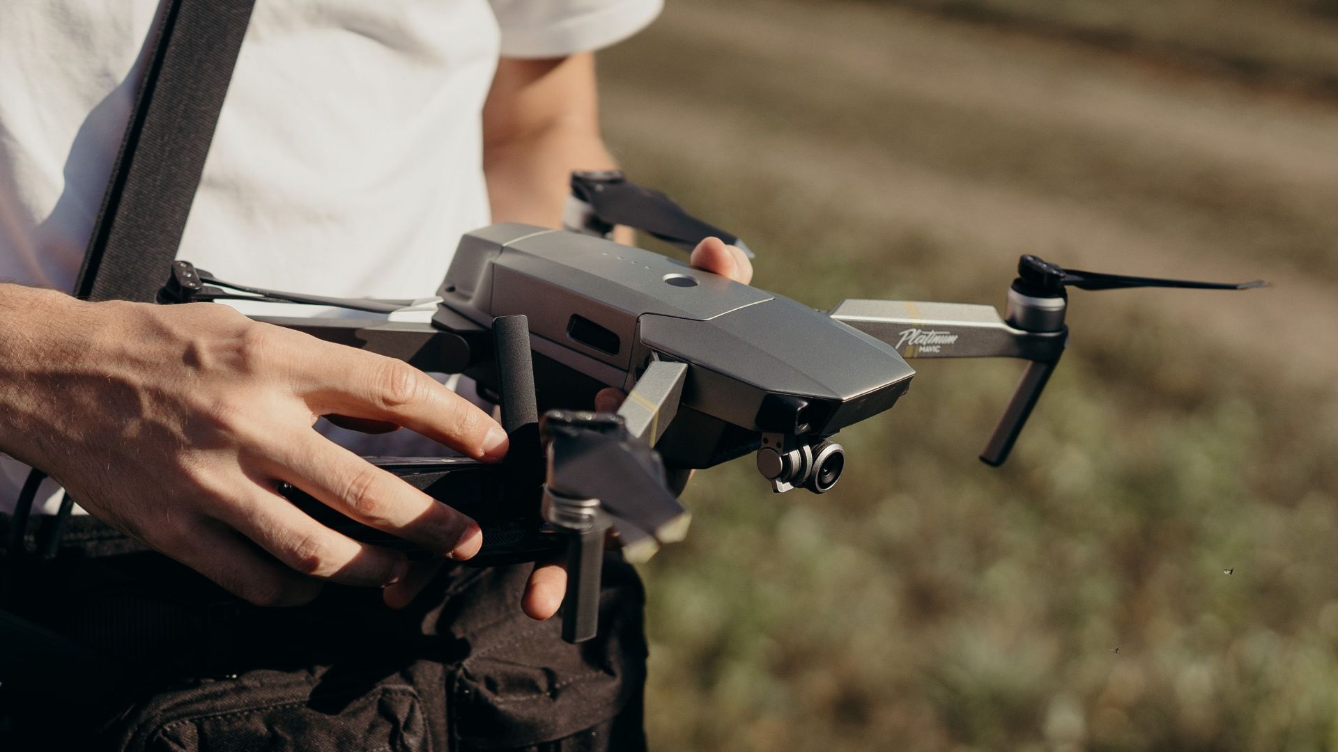 Close-up of a man holding a drone outdoors, showcasing drone technology preparation.