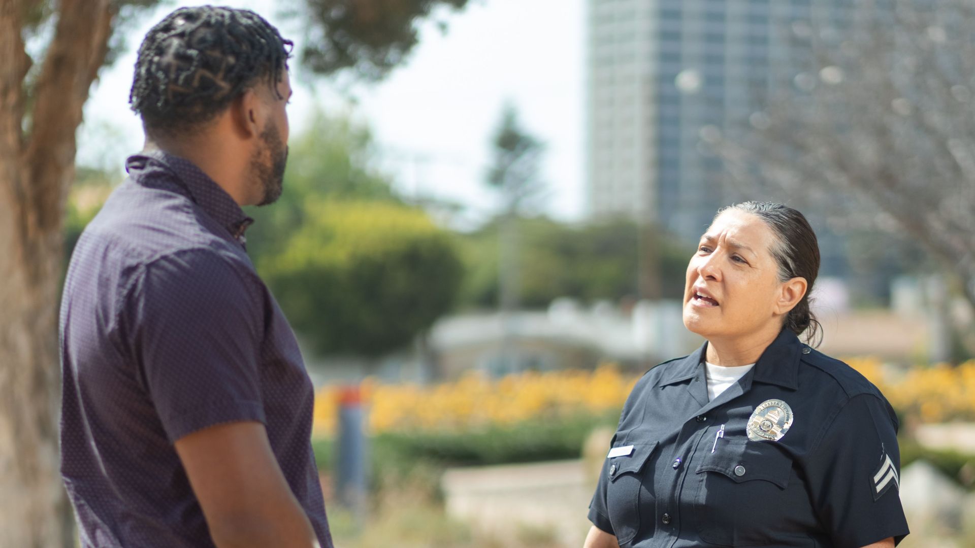 A police officer in uniform converses with a man on a sunny day, showcasing community engagement.