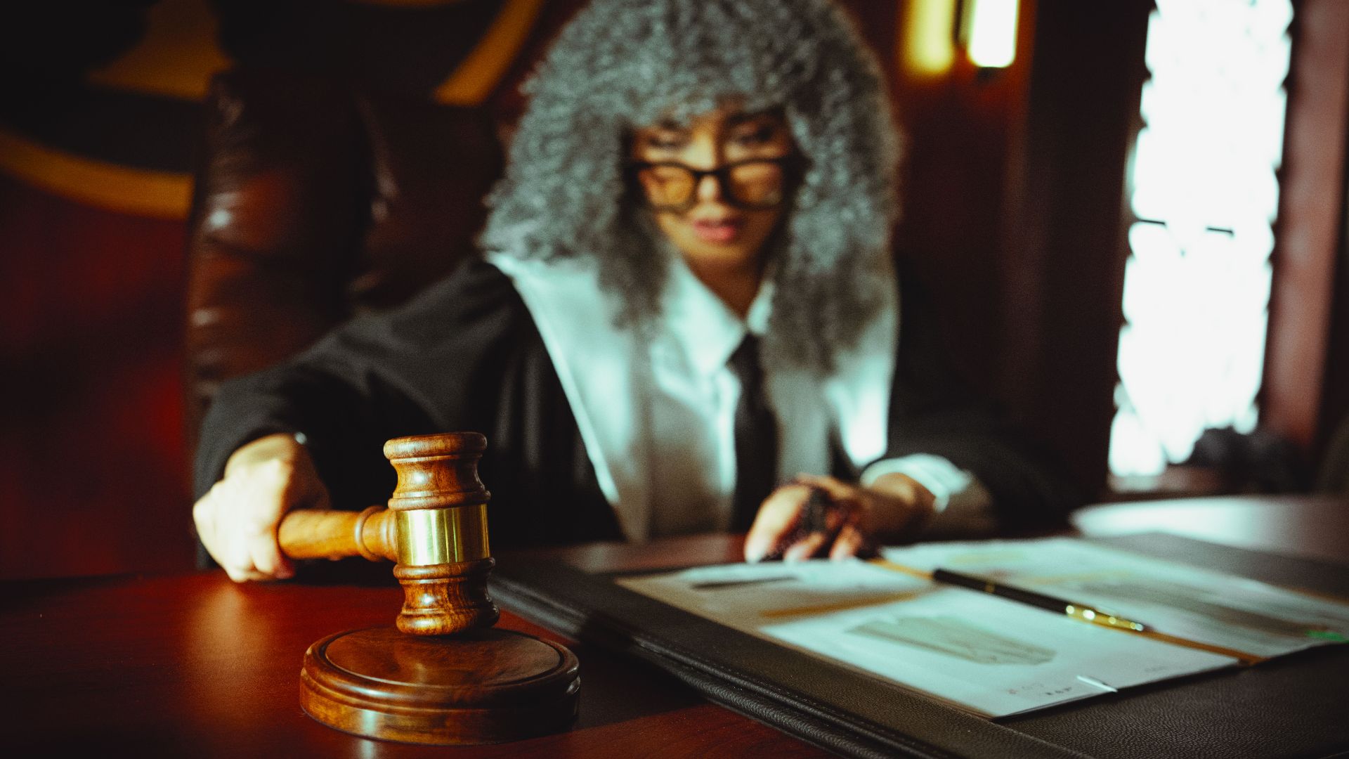 Female judge in a courtroom setting, focusing on legal documents with a gavel.