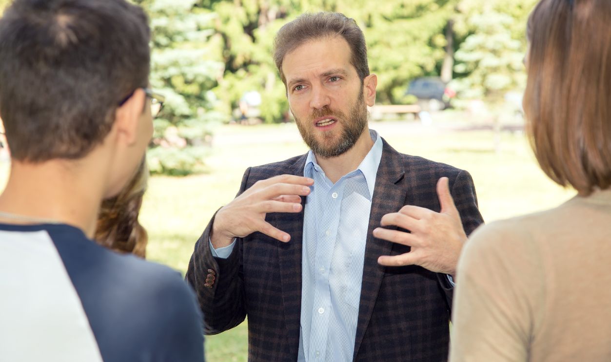 Discussion. Speaker teacher talks with a group of students near the university.