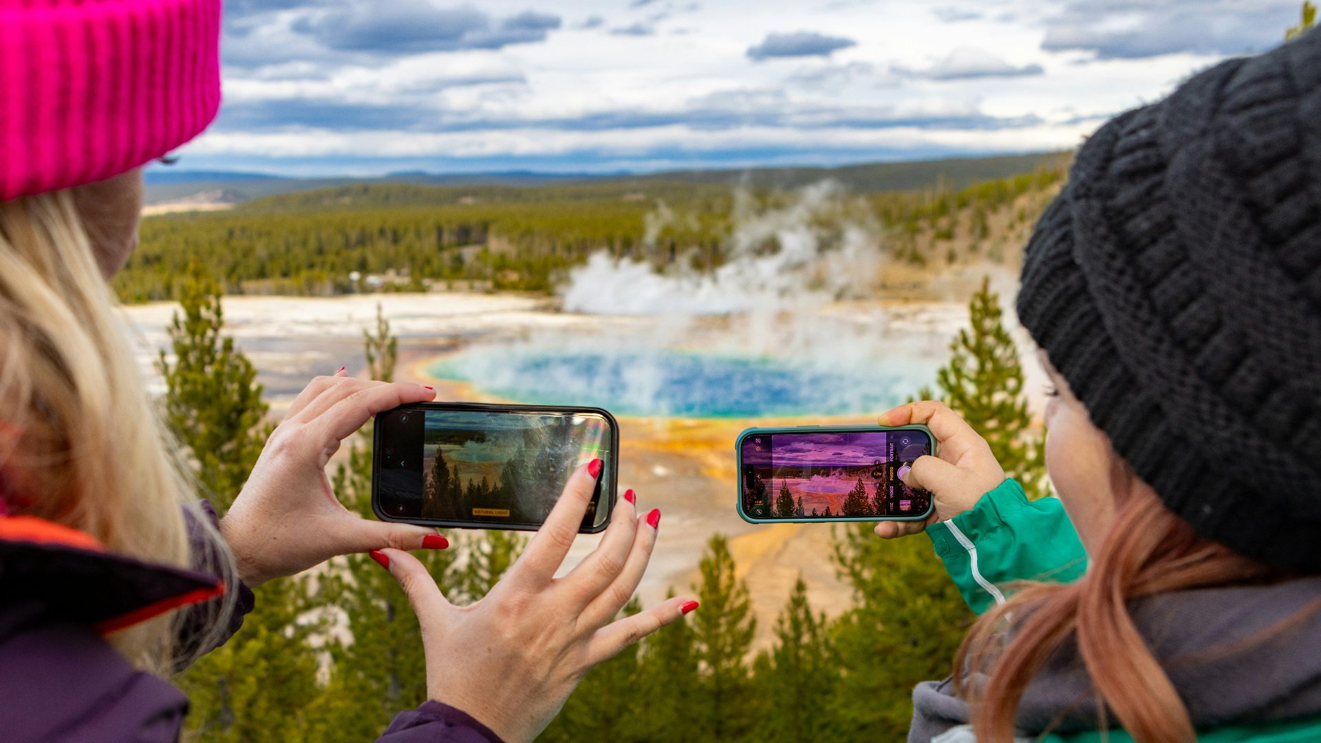 Two people taking photos of a hot spring.