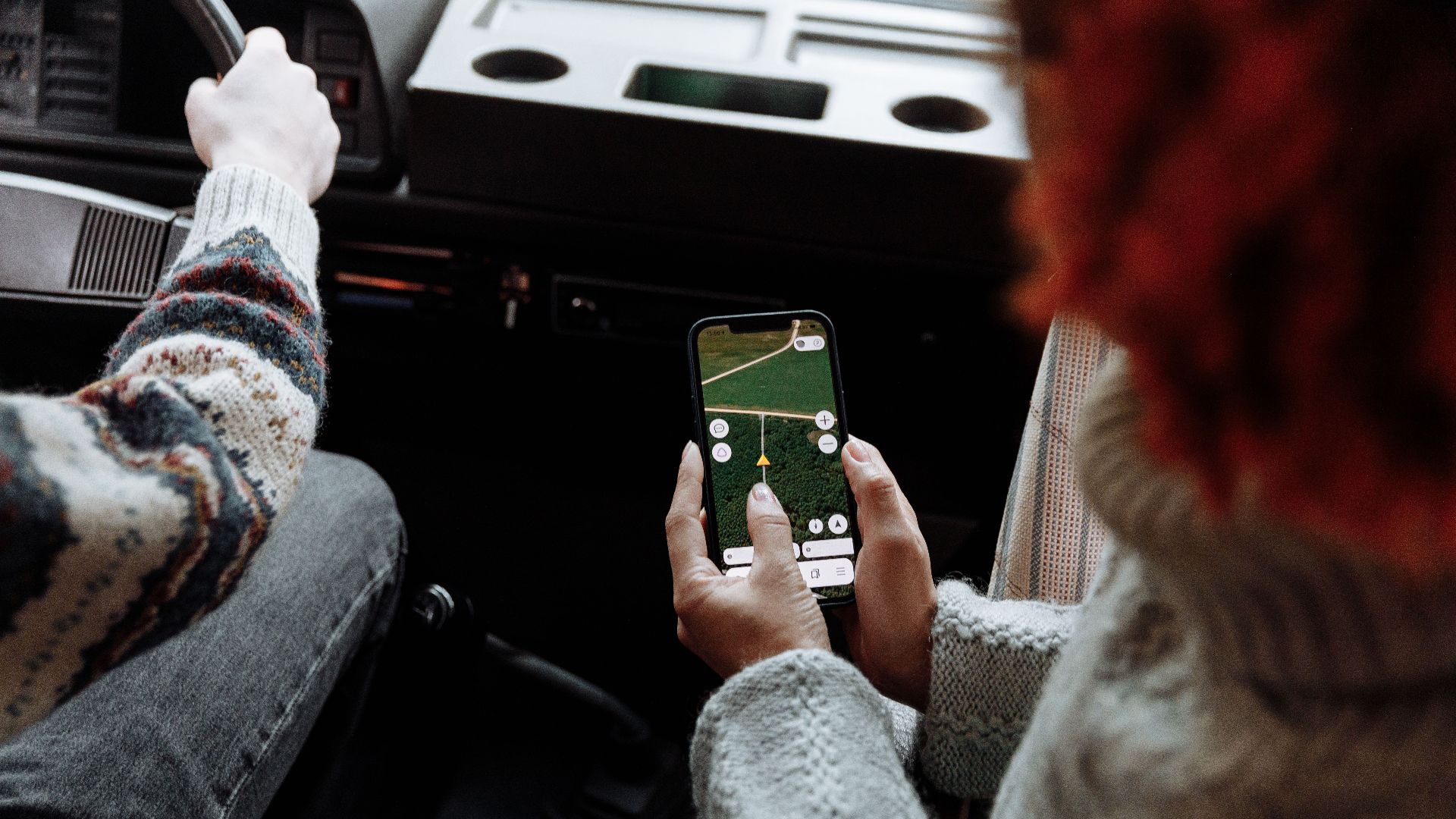 Two people using a navigation app on a smartphone during a road trip