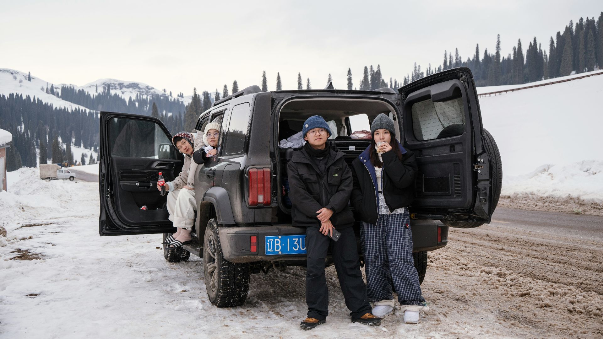 People gathered around a car in a snowy landscape.