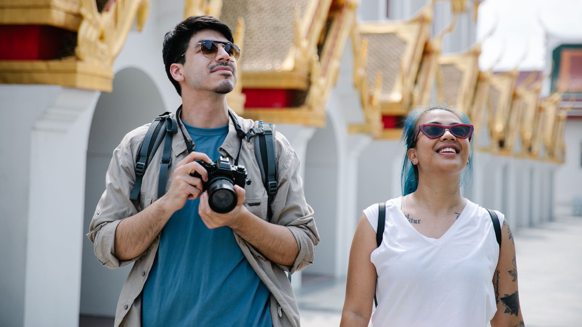 A couple explores a city's ornate architecture, capturing memories with a camera.