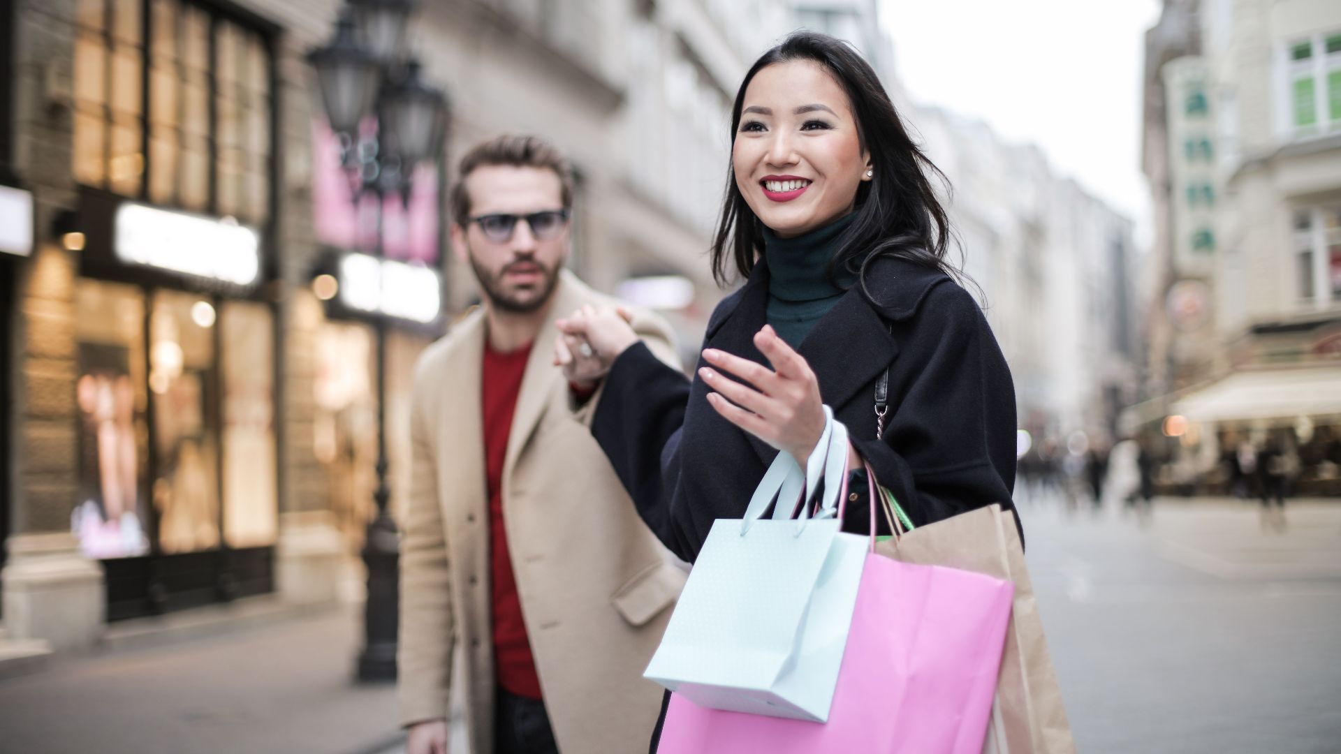 Joyful couple shopping and enjoying a sunny day in the city with shopping bags. Perfect for lifestyle and urban tourism themes.