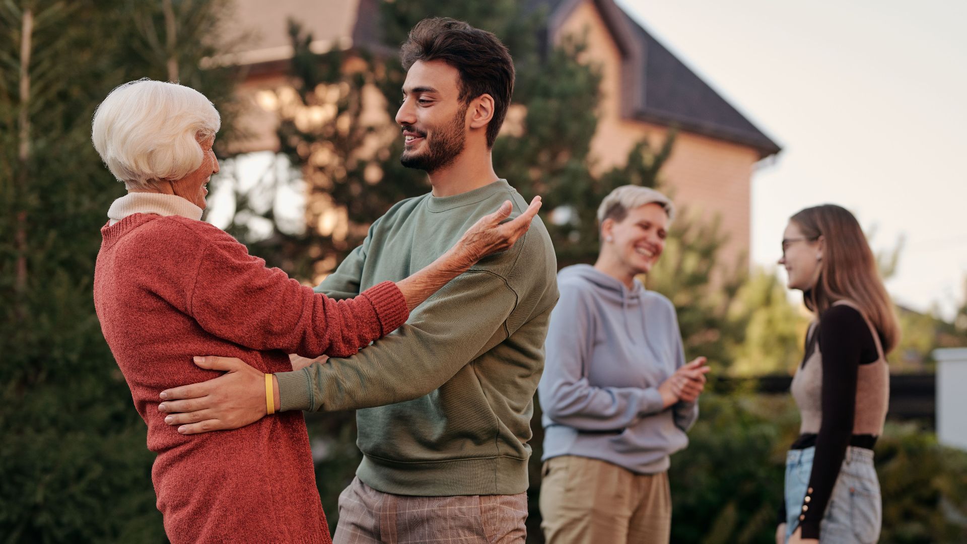 A joyful family gathering outdoors with diverse generations embracing and smiling.