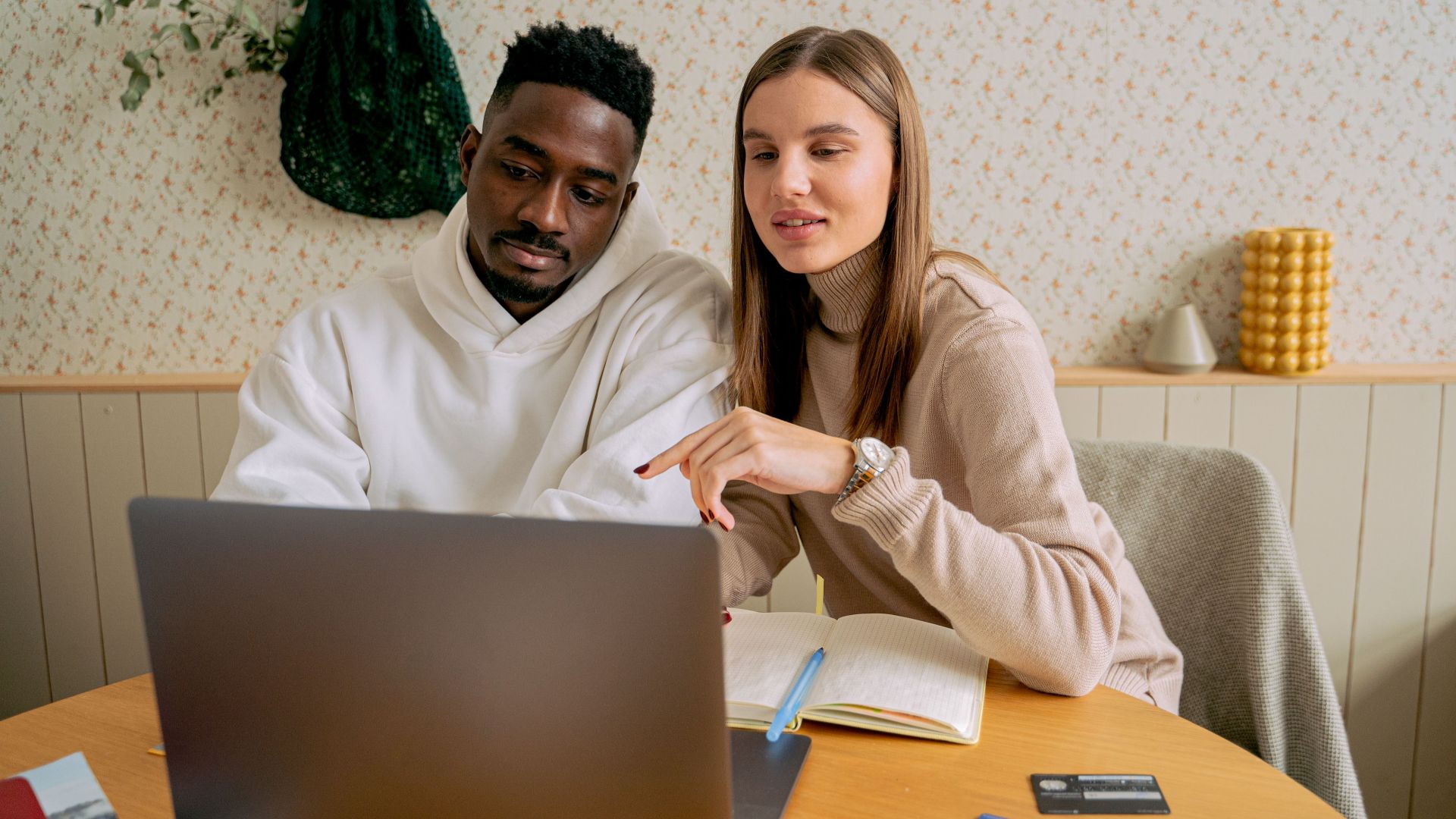 An interracial couple engaged in collaborative work on a laptop indoors, fostering teamwork.