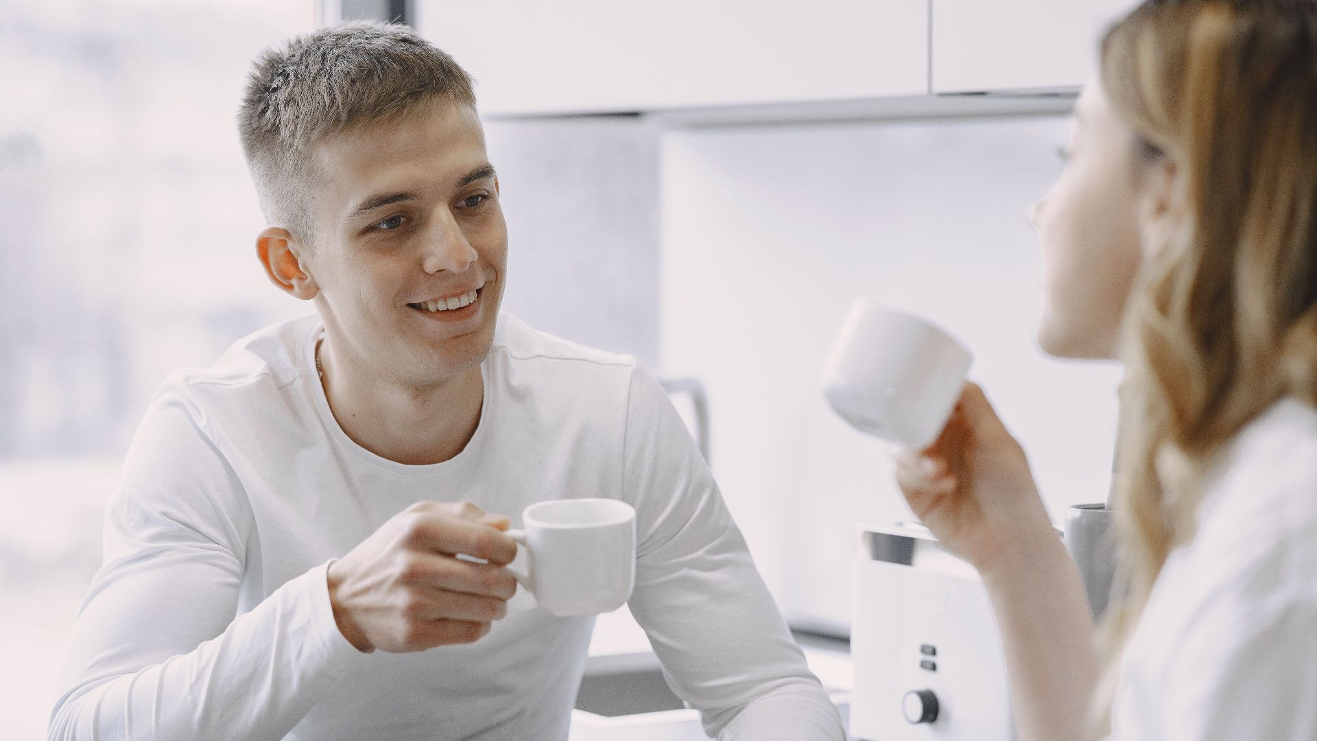 Smiling couple sharing a moment over coffee, highlighting warmth and connection.