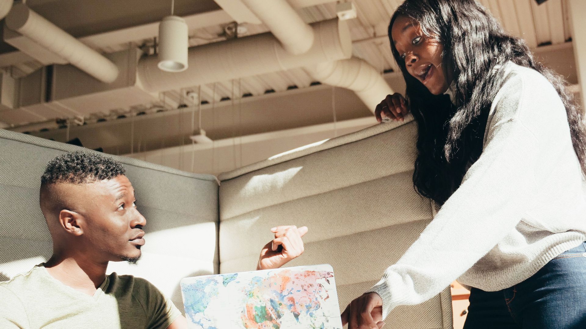 Two colleagues engaging in a discussion with a world map in a modern office setting.